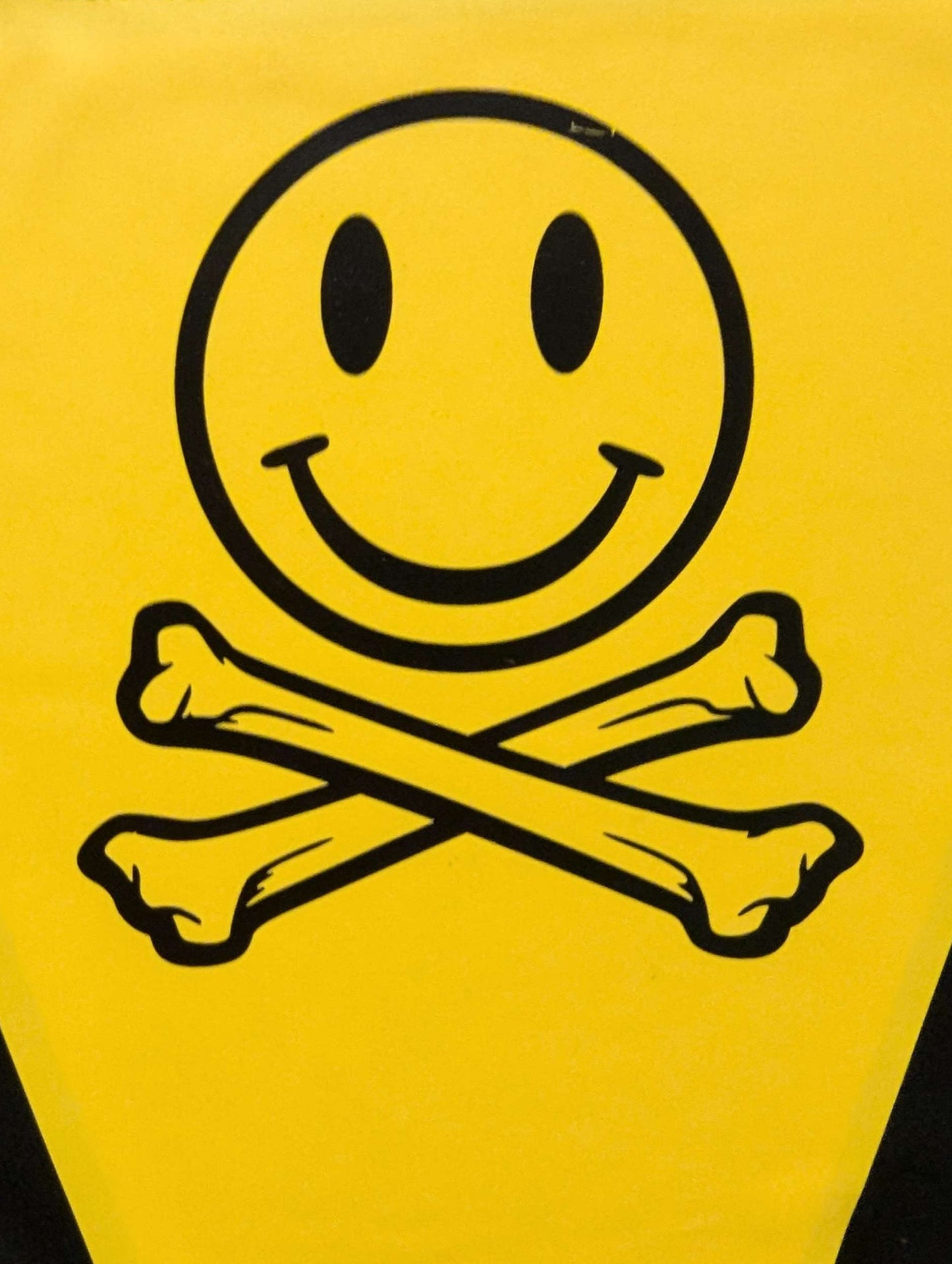 Yellow triangle with a smiley face and crossbones design on a black background