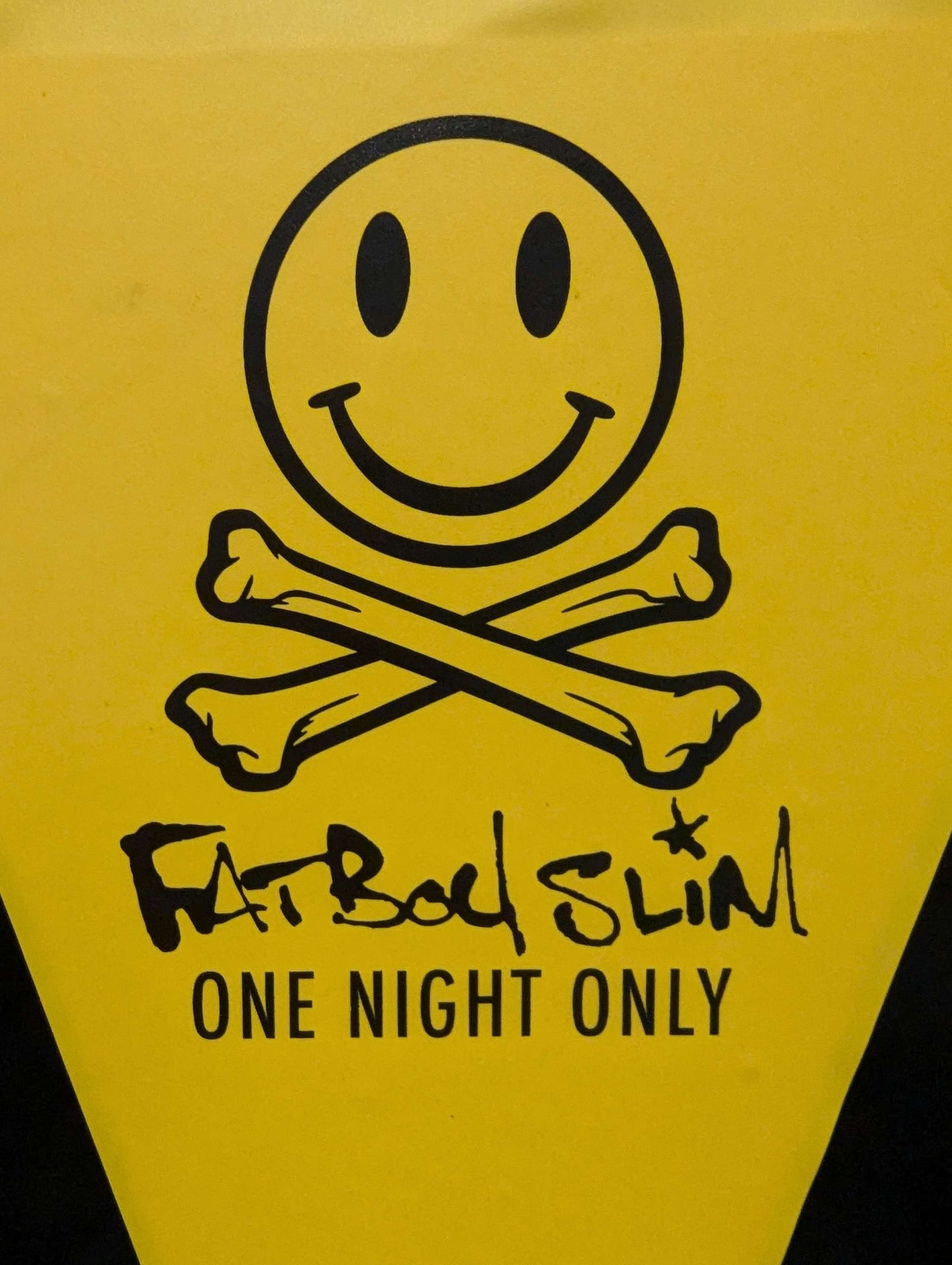 Yellow poster with a smiley face and crossbones design, featuring 'Fatboy Slim One Night Only' text.