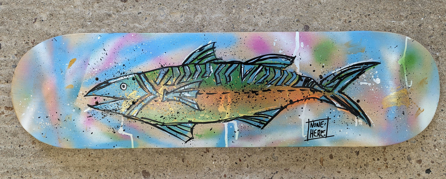 Steve McCracken painted skateboard, freehand style colourful fish with greens and blue fins painted on a background of blue and pink spray and splatter. skateboard is resting on a concrete floor.
