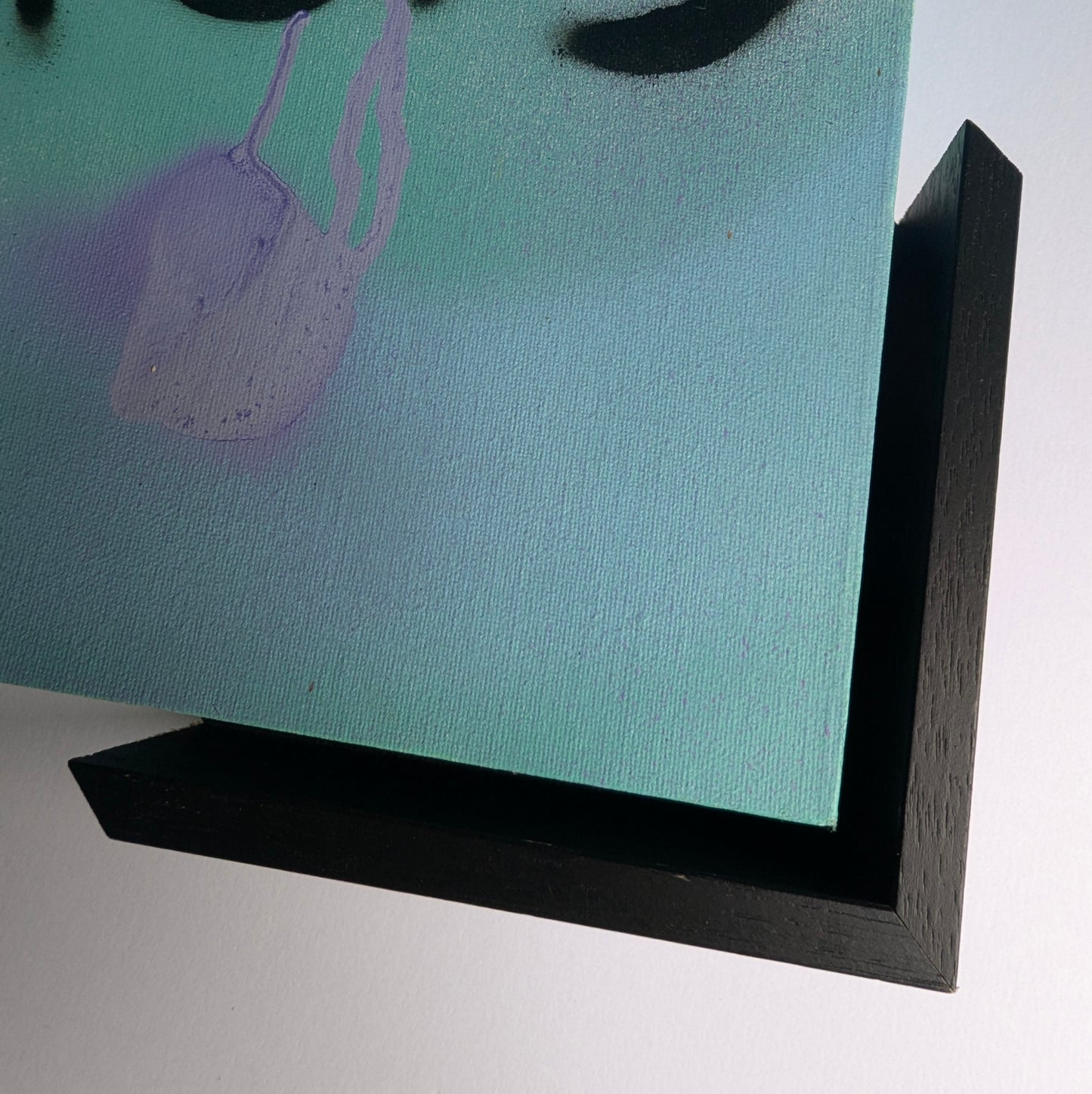 Close-up of a teal painting with a black frame on a white background