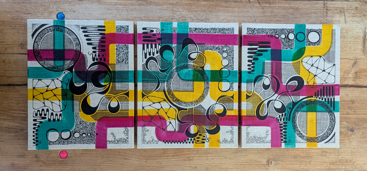 triptych colourful doodles on off white panels, placed on wooded table