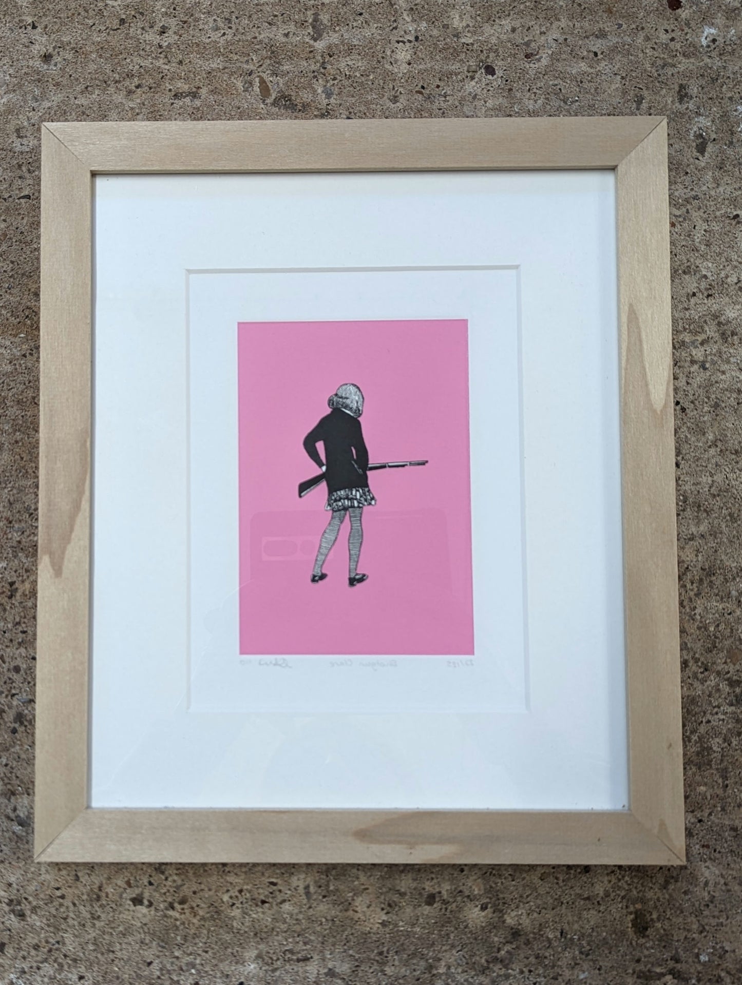 front on view of CEAL WARNANTS 'SHOTGUN CLARE' Ltd Ed Print framed in tulip wood with white mountboard, artwork is of a girl with back to us holding a rifle, the styel is 1940s sketch on vivid pink background.
