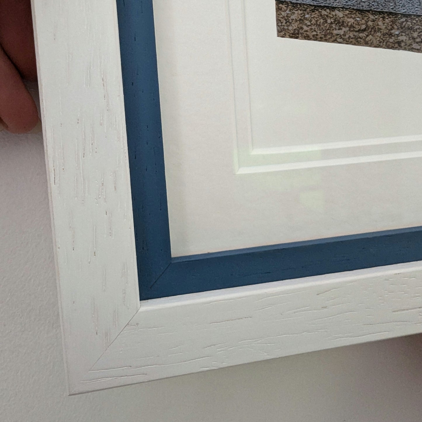 Close-up of a white picture frame with blue inner border on a white background.