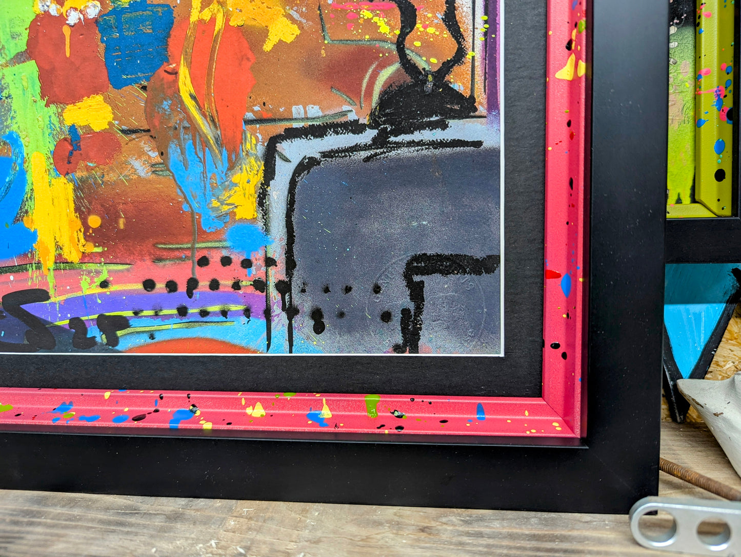 close up of the smooth black picture moulding and the internal custom painted frame, frame is red with blue yellow green splatters
