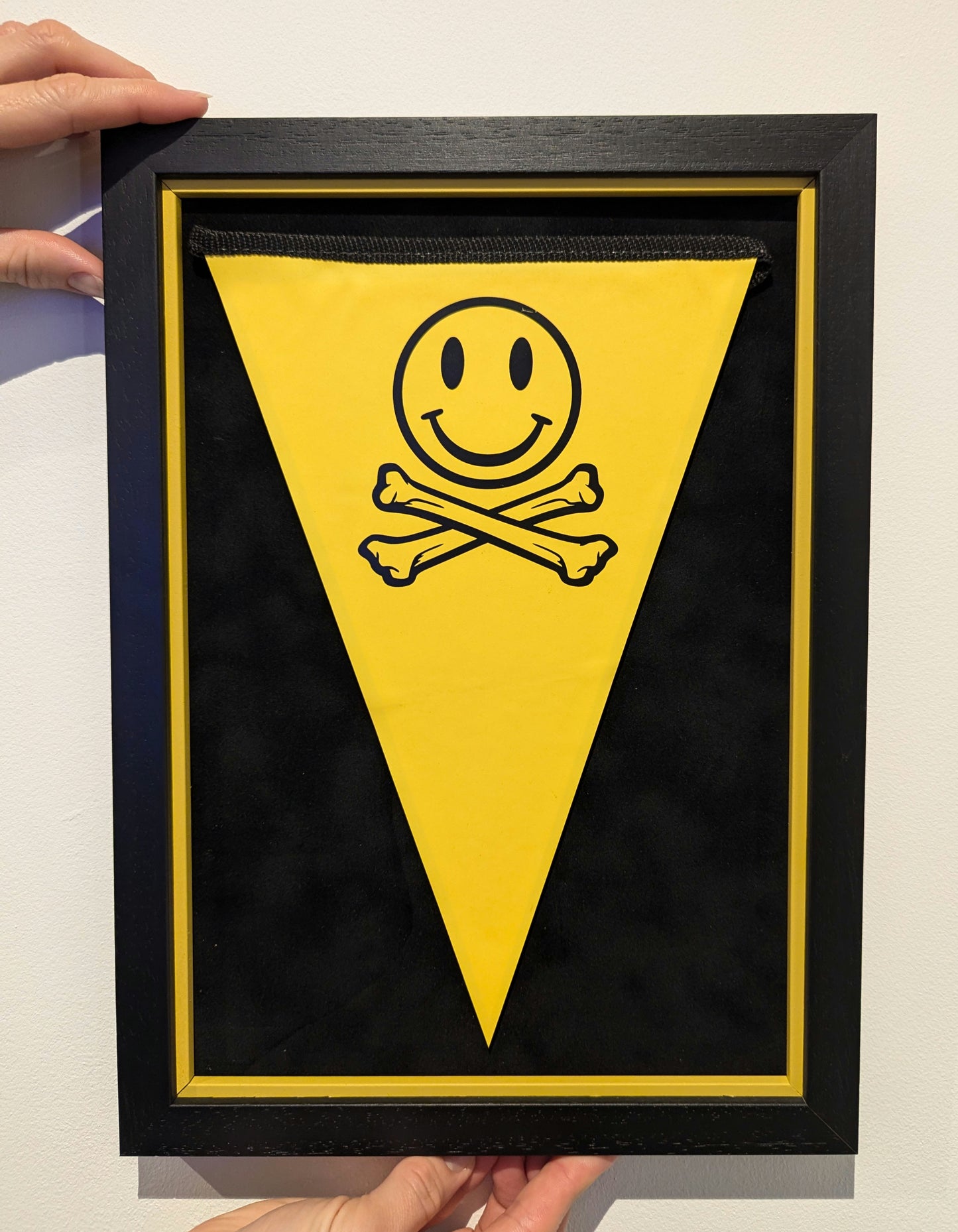Framed yellow triangle with smiley face and crossbones design, Fatboy Slim