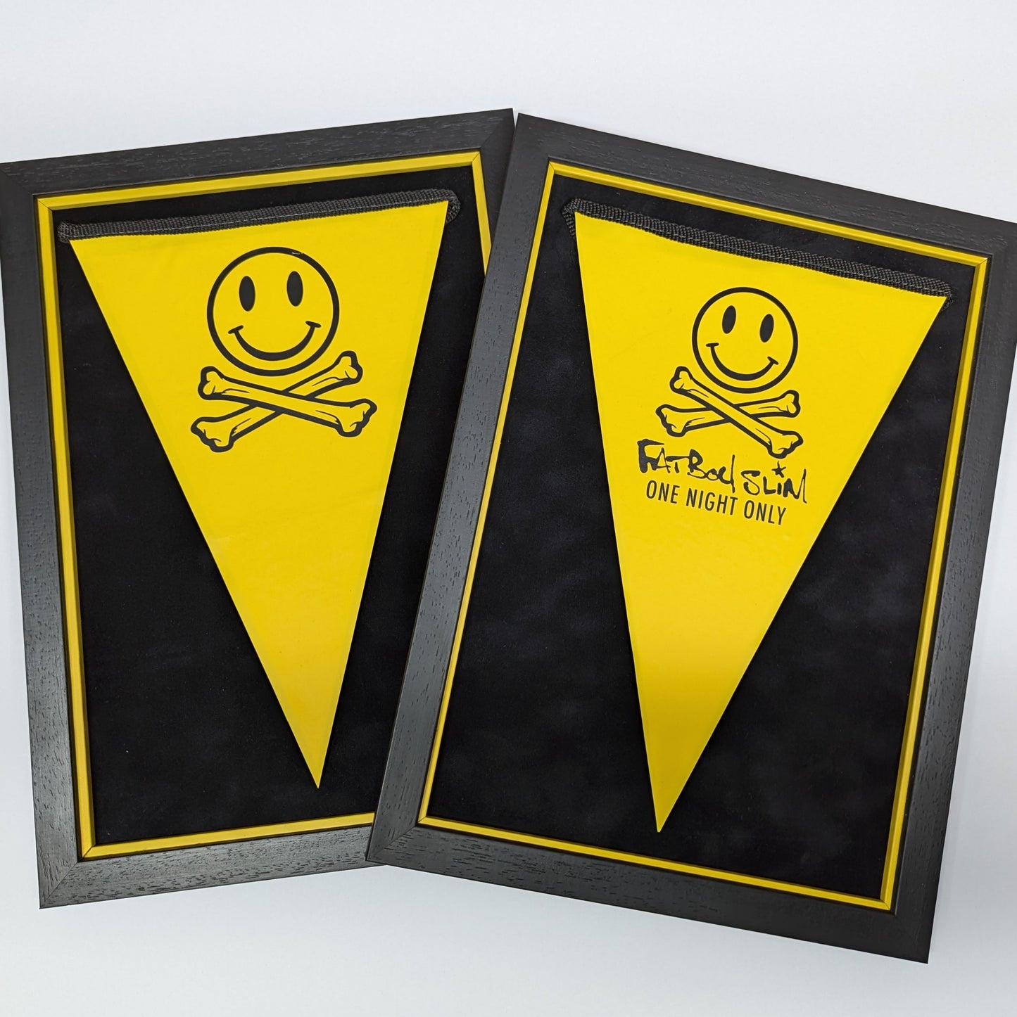 two black and yellow picture frames both have yellow bunting float mounted, smiley face and cross bones