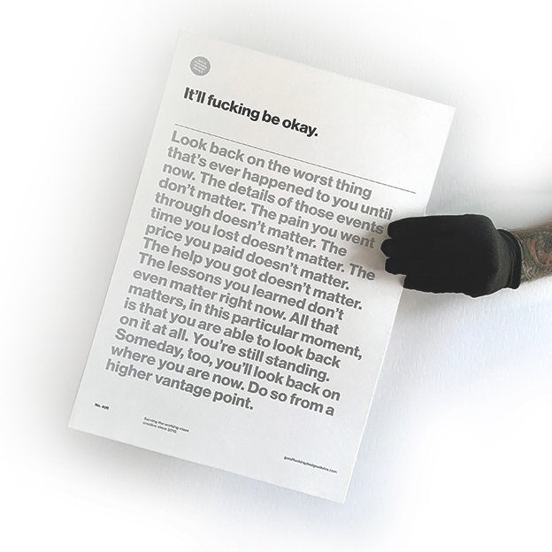 good fucking design advice "it'll fucking be okay" being held by a person wearing a black glove, print is white with black and silver text