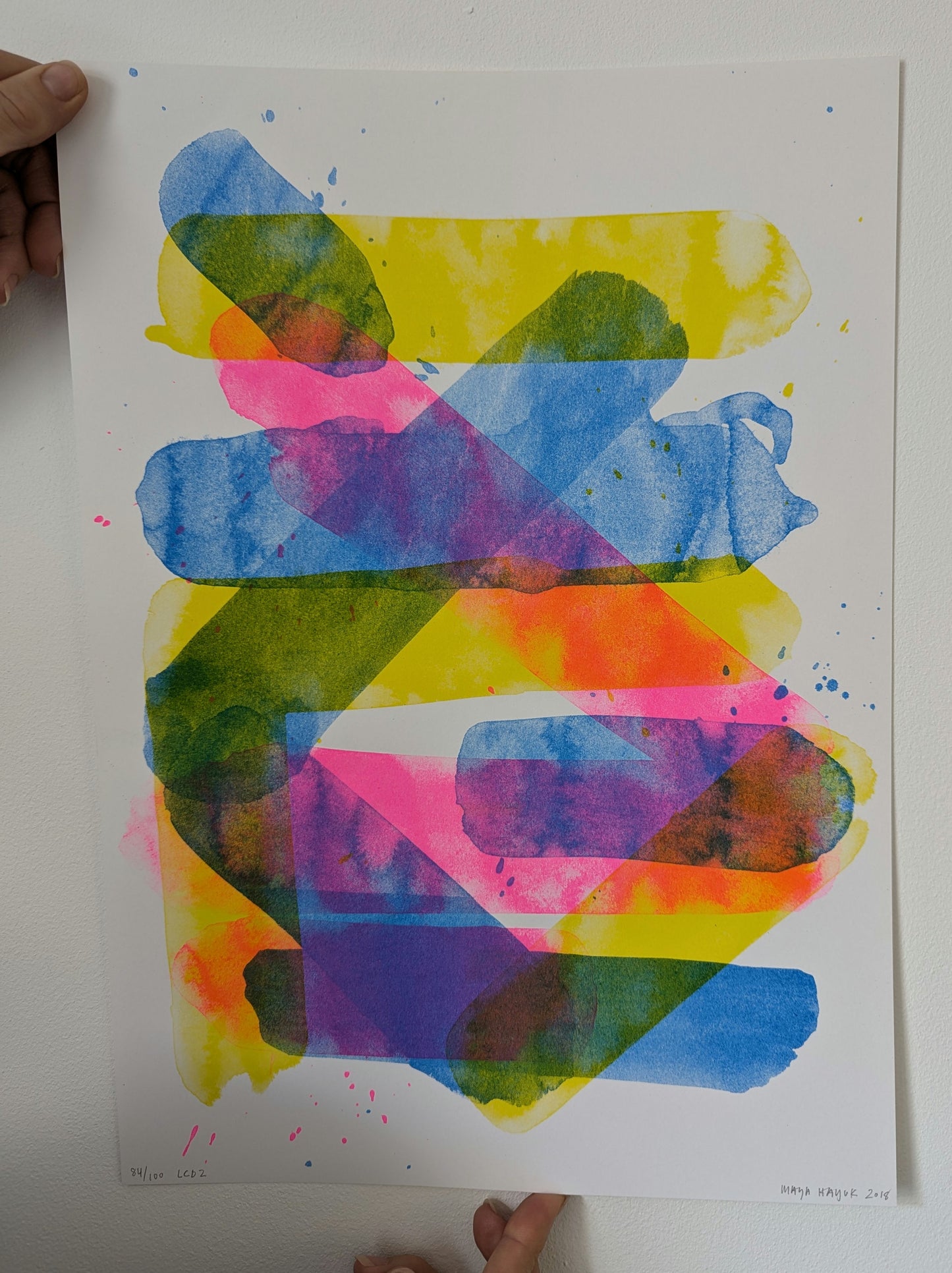 Colorful abstract art print held by a person on a white background being held by two hands