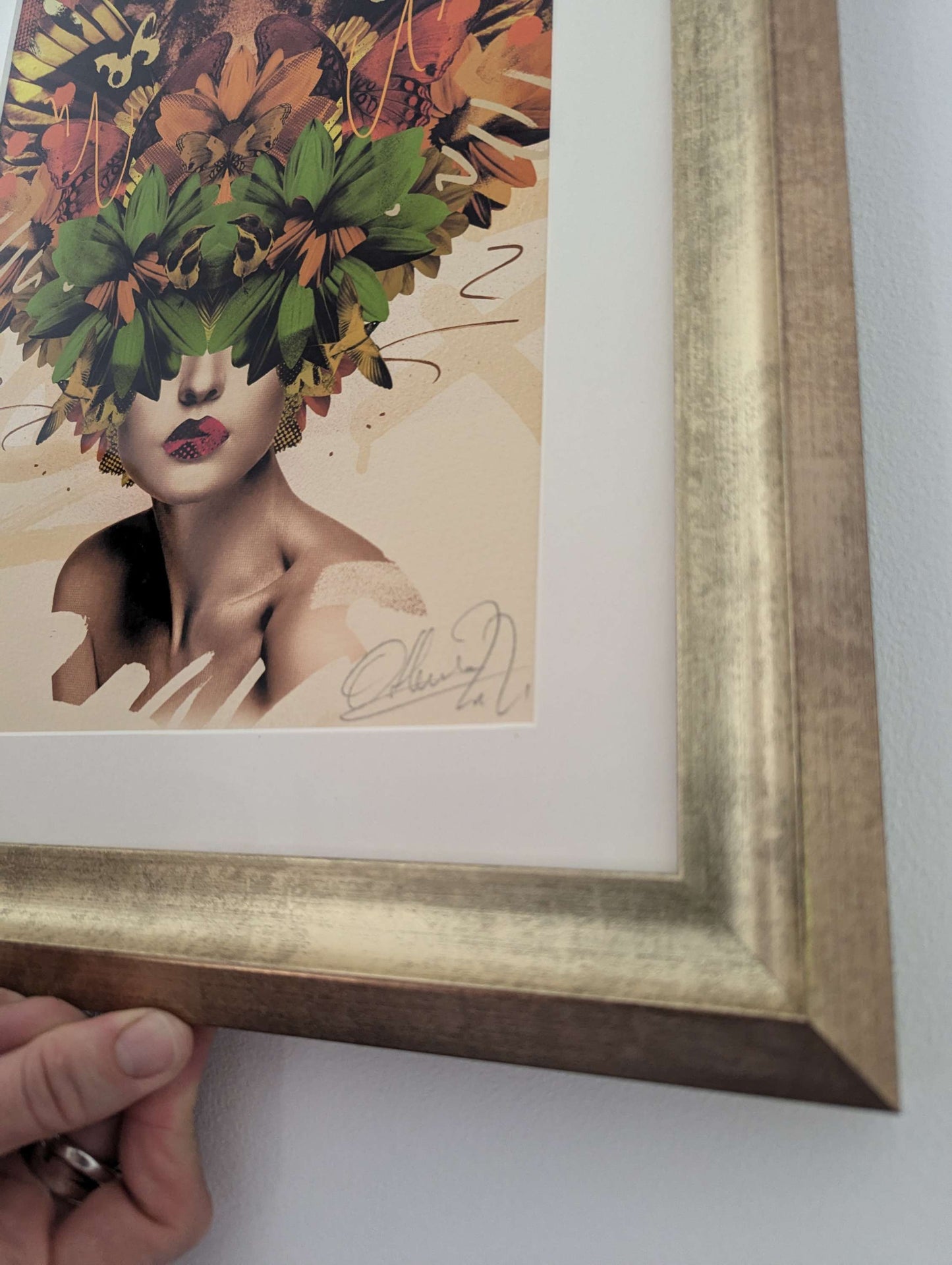 olly howe artwork on gold frame, the artwork is a collage style a womans face but her eyes and head are leaves and a tiger face, side of picture.