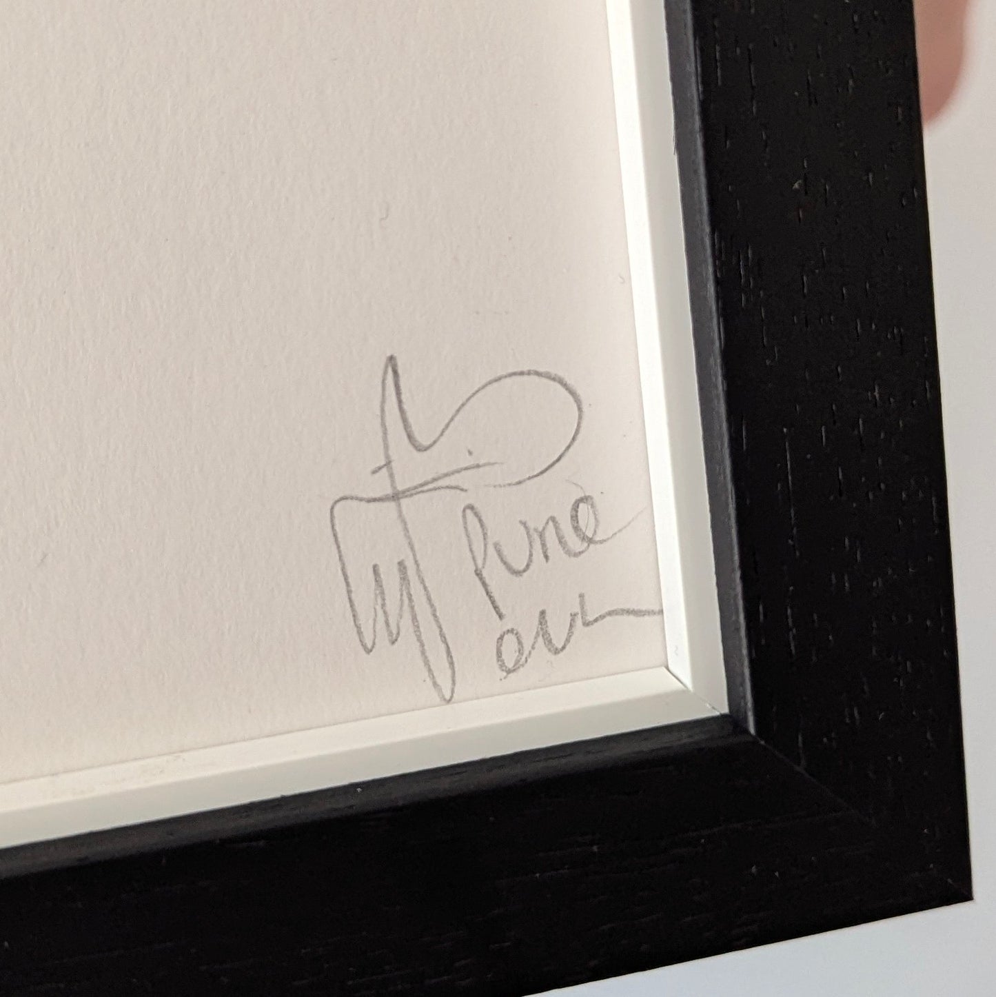 Close-up of a framed piece of art with a pure evil signature on a white background