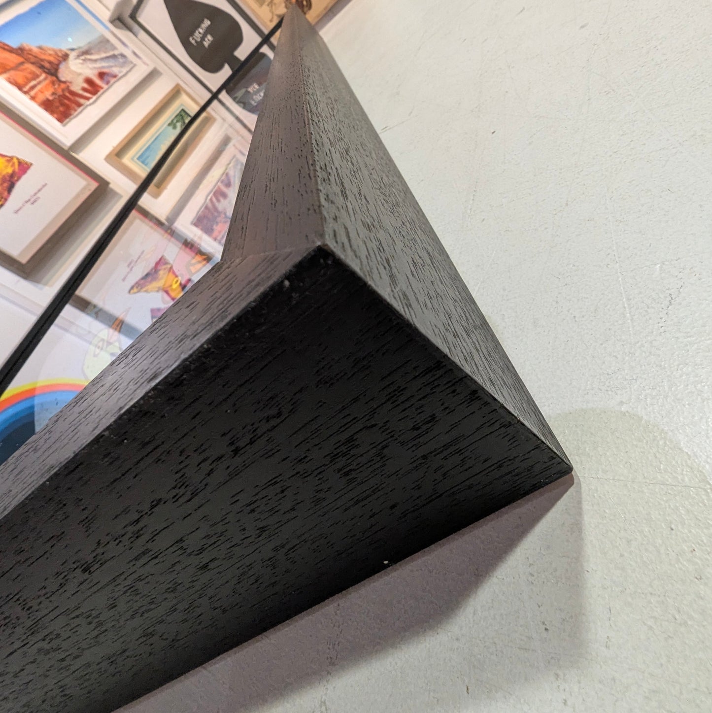 Close-up of a dark wooden picture frame against a light wall with framed pictures.