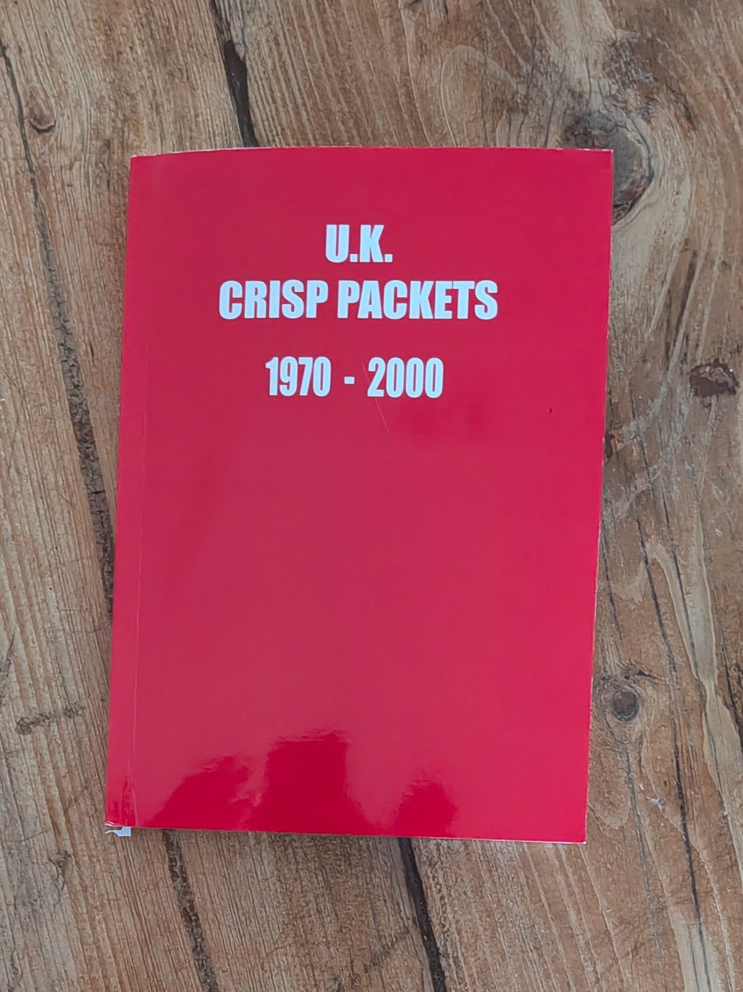 Red book titled 'U.K. Crisp Packets 1970-2000' on a wooden surface