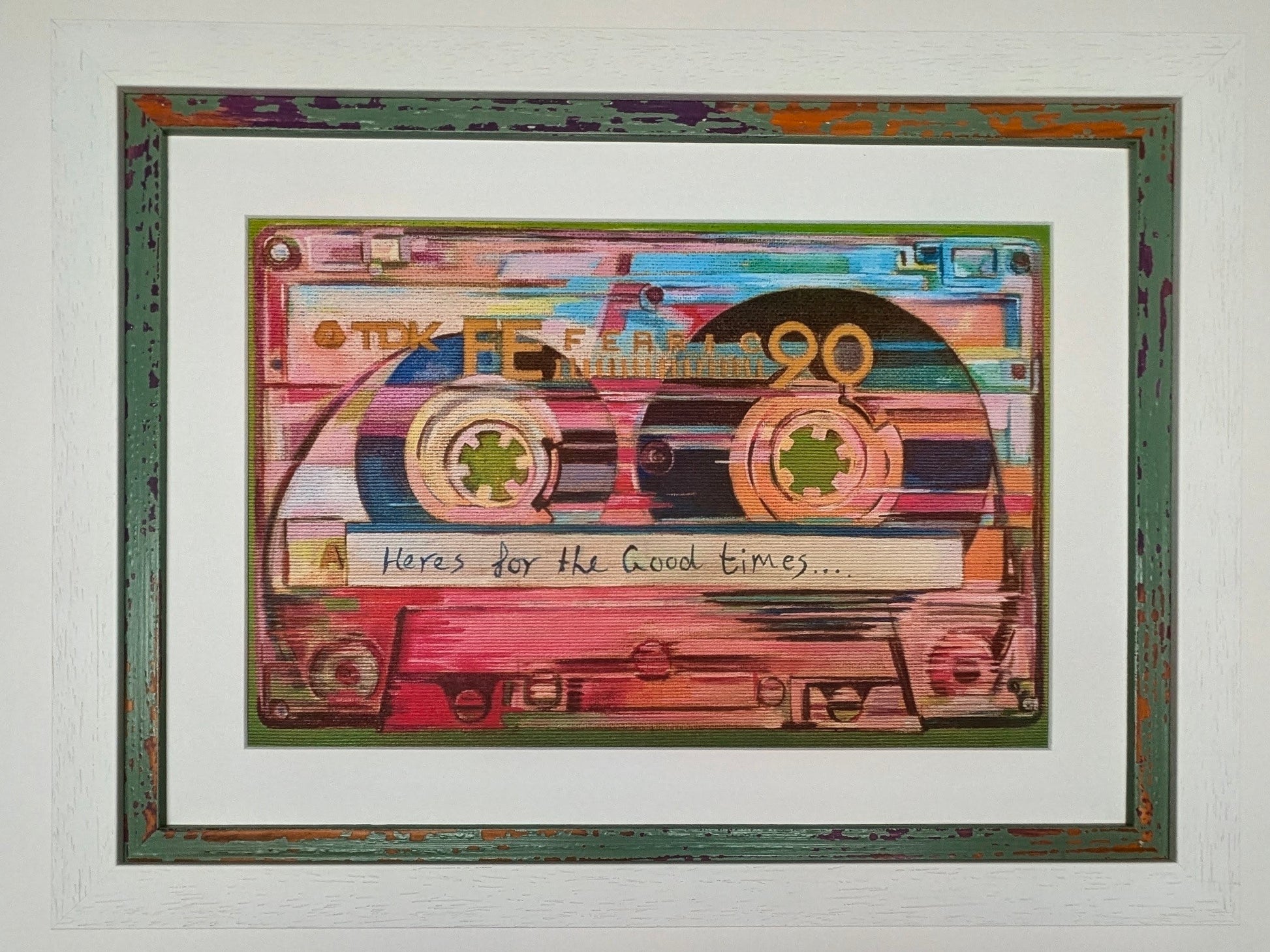 A framed art print depicting a colourful, stylized cassette tape with the handwritten text 'Here's for the Good Times.
