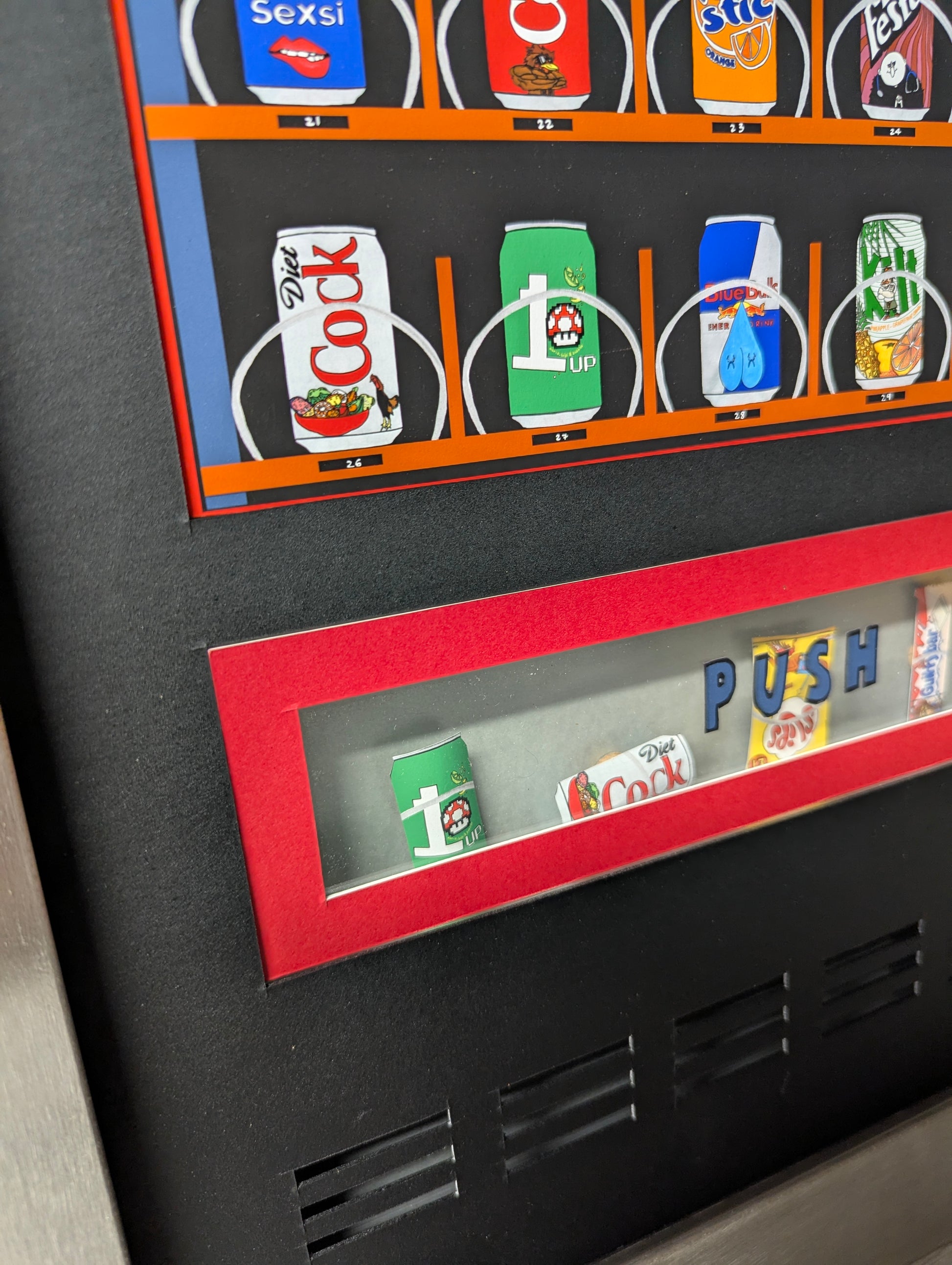 art work shows a close up of cartoon vending machine by multi ego,  it shows the food retrieval flap, it has been custom framed in a welded stainless steel frame.