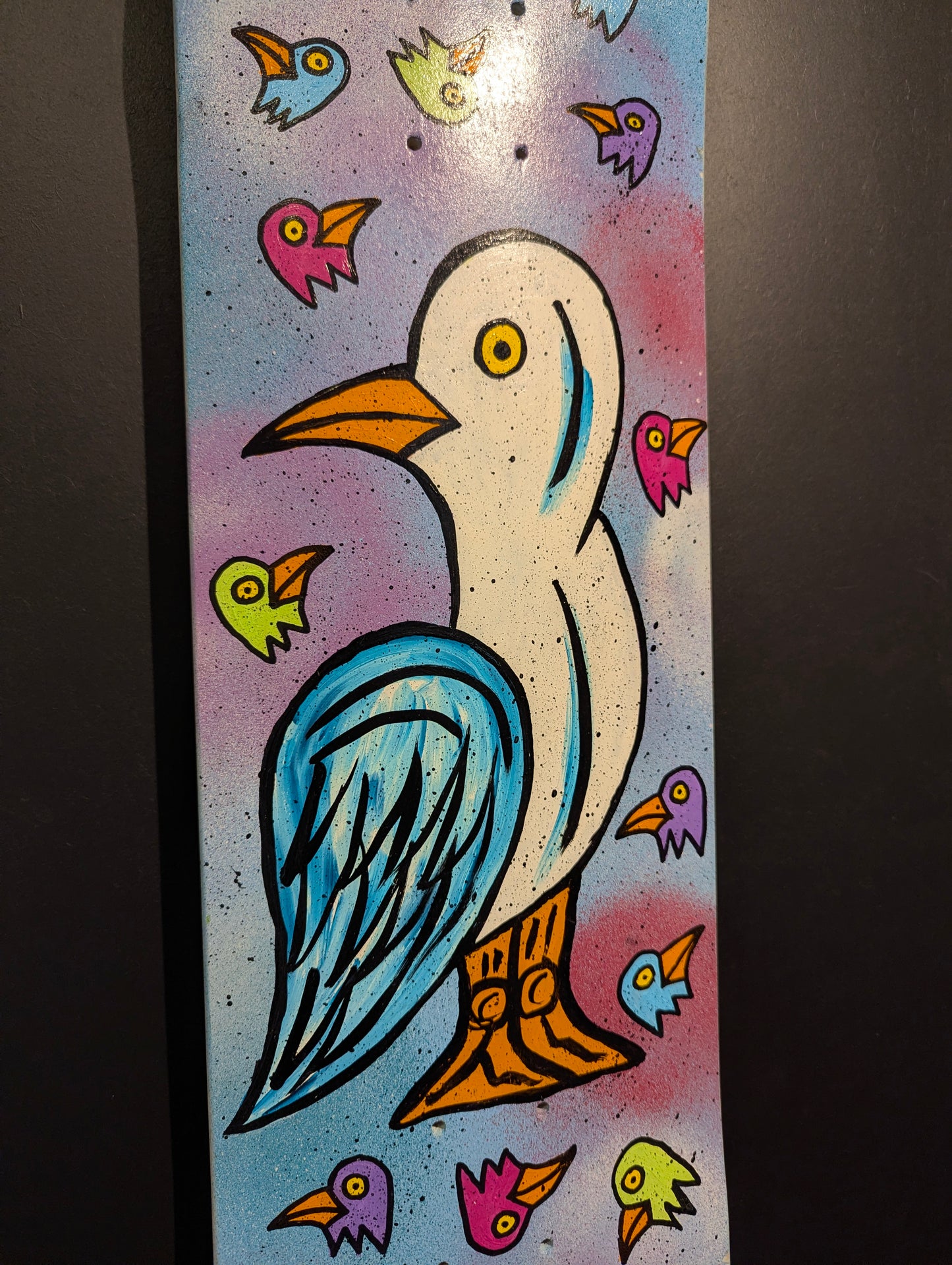 Colorful illustration of a bird on skateboard with small bird-like creatures around it on a gradient background.