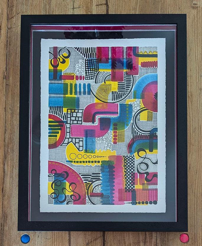 black frame against a wood background, colourful doodle shades of pink, blue, yellow and black. artwork by clare capper.