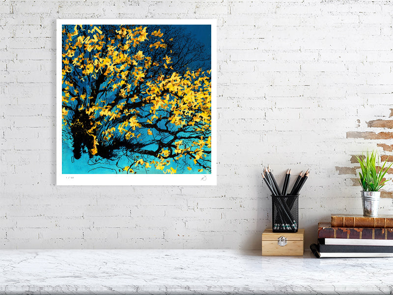 abstract artwork with yellow flowers on a blue background, displayed on a white brick wall above a desk.