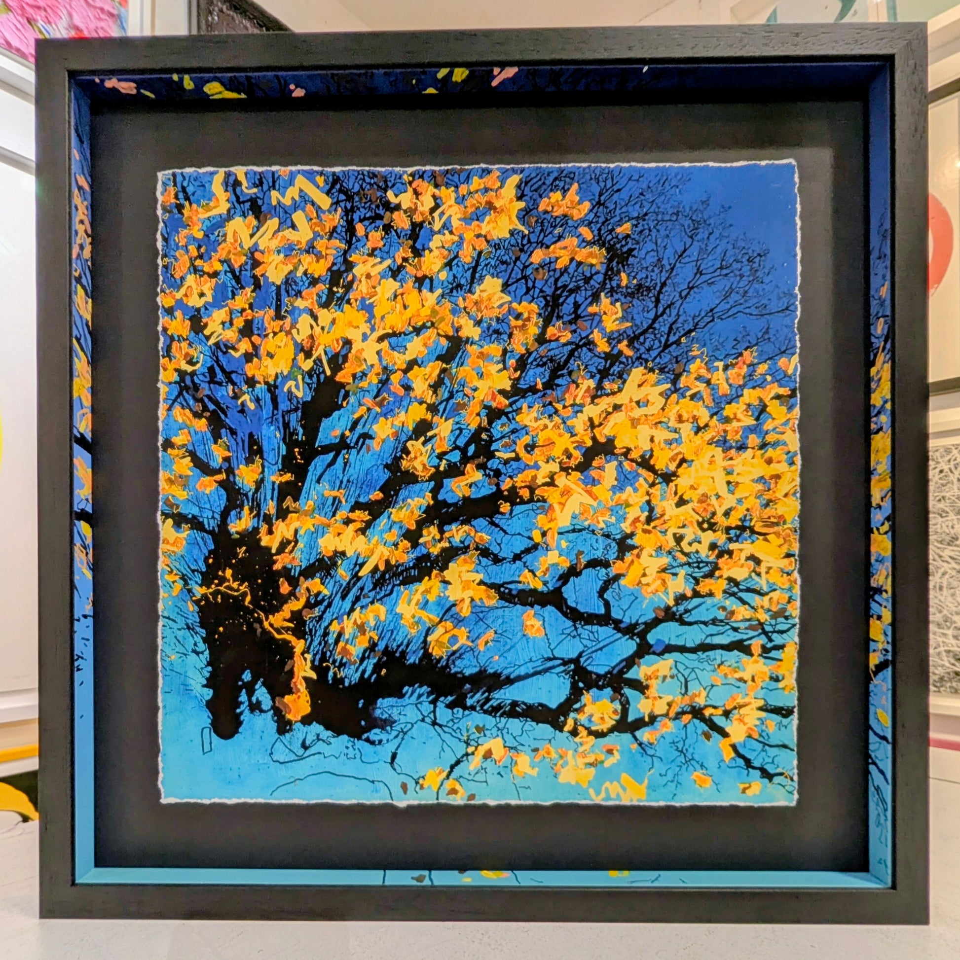 Framed artwork of a tree with yellow leaves against a blue sky