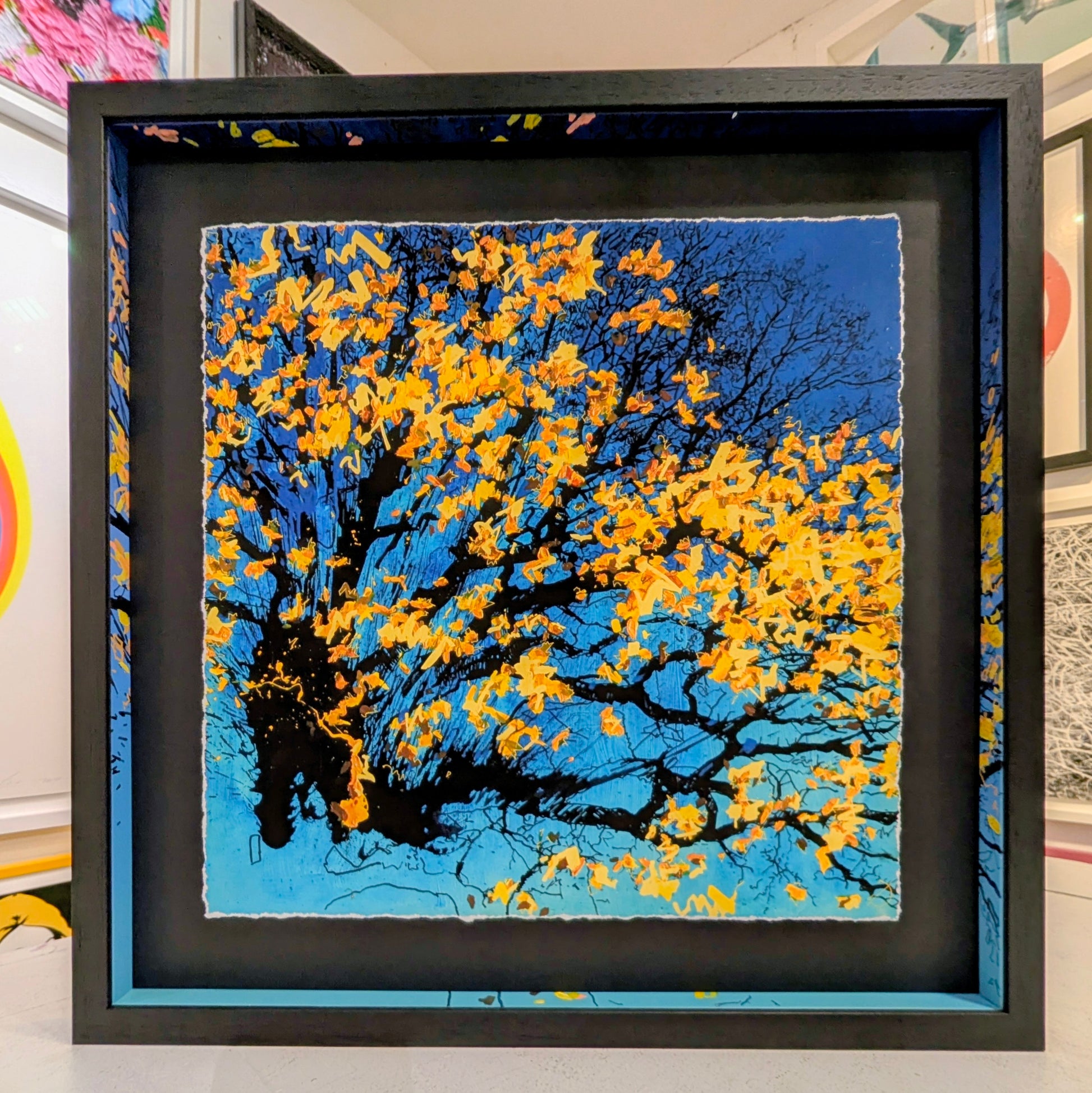 Framed artwork of a tree with yellow leaves against a blue sky