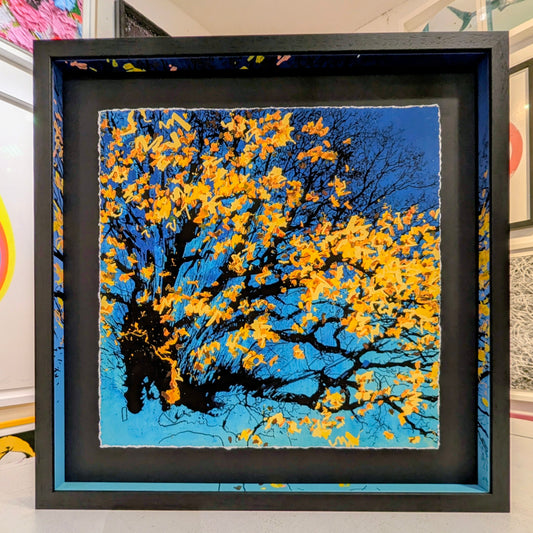 Framed artwork of a tree with yellow leaves against a blue sky