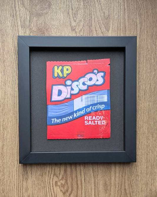 Framed red crisp packet with 'KP Disco's' branding on a wooden surface