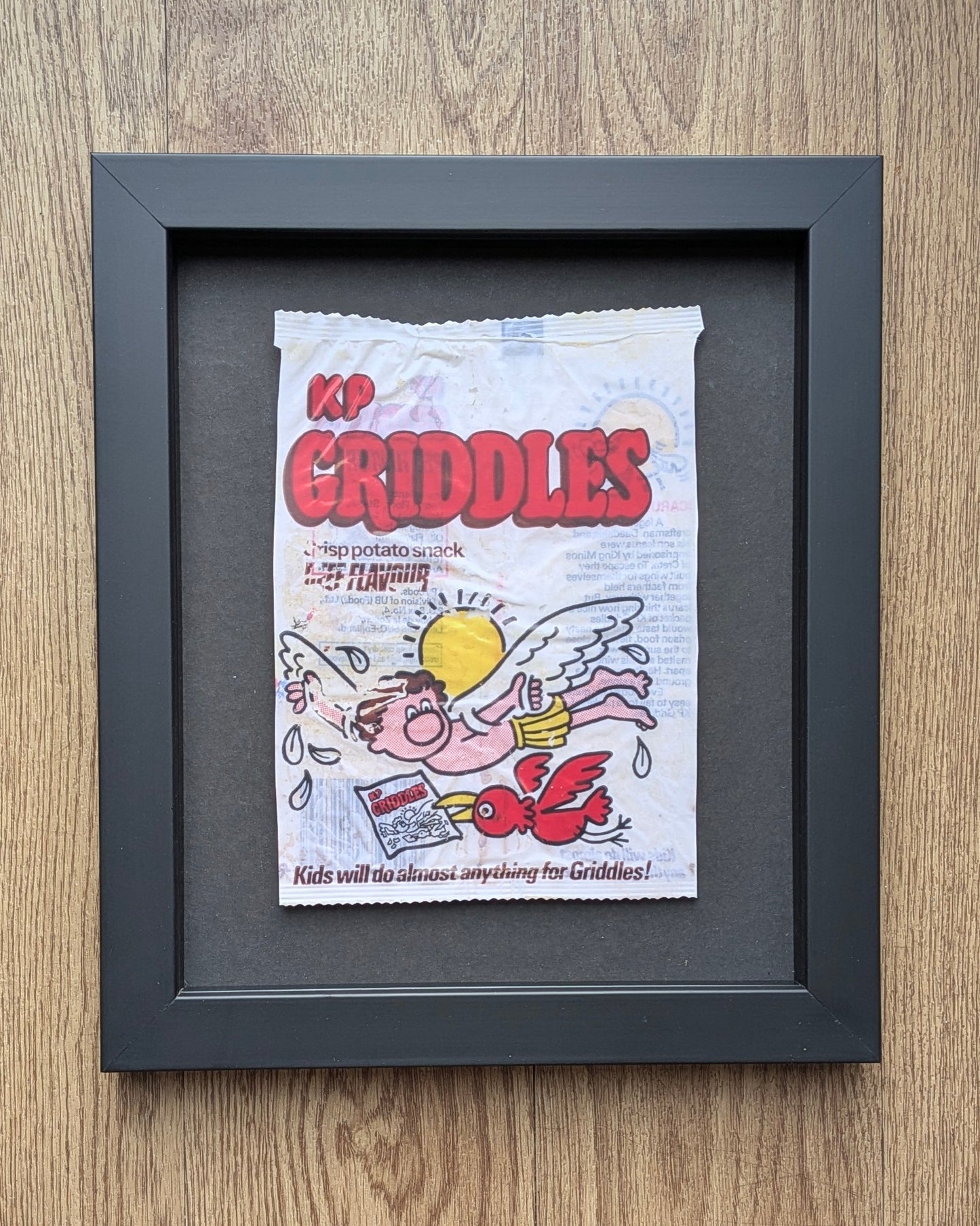 Framed vintage Criddles snack packet on a wooden surface