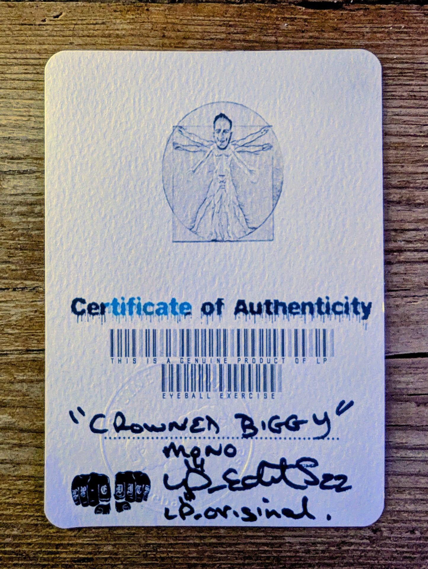 Certificate of Authenticity with a barcode and text on a wooden surface