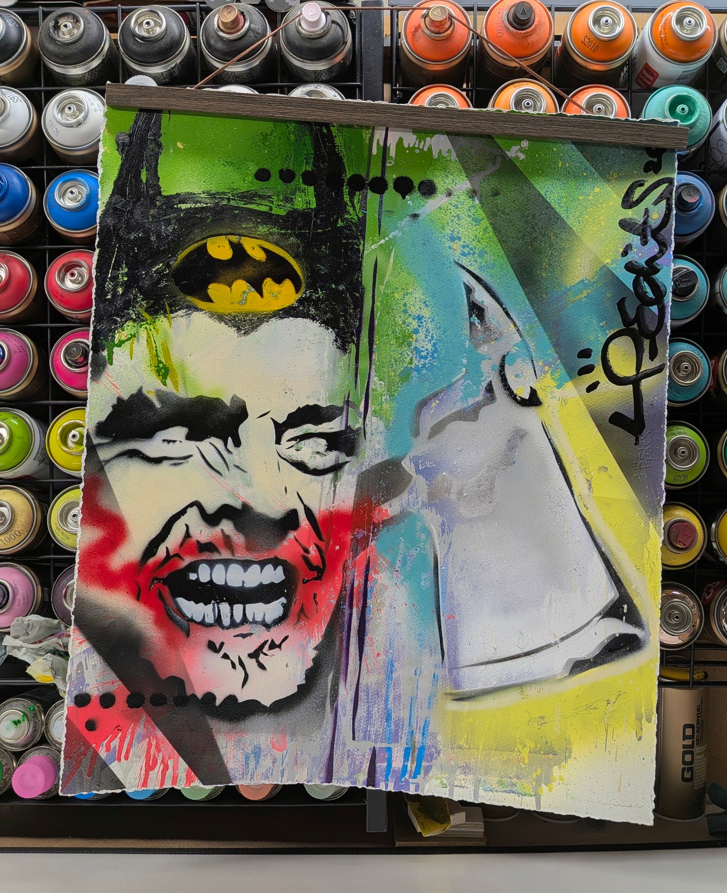 Artistic depiction of a face with a bat symbol and a knife, surrounded by spray paint cans.