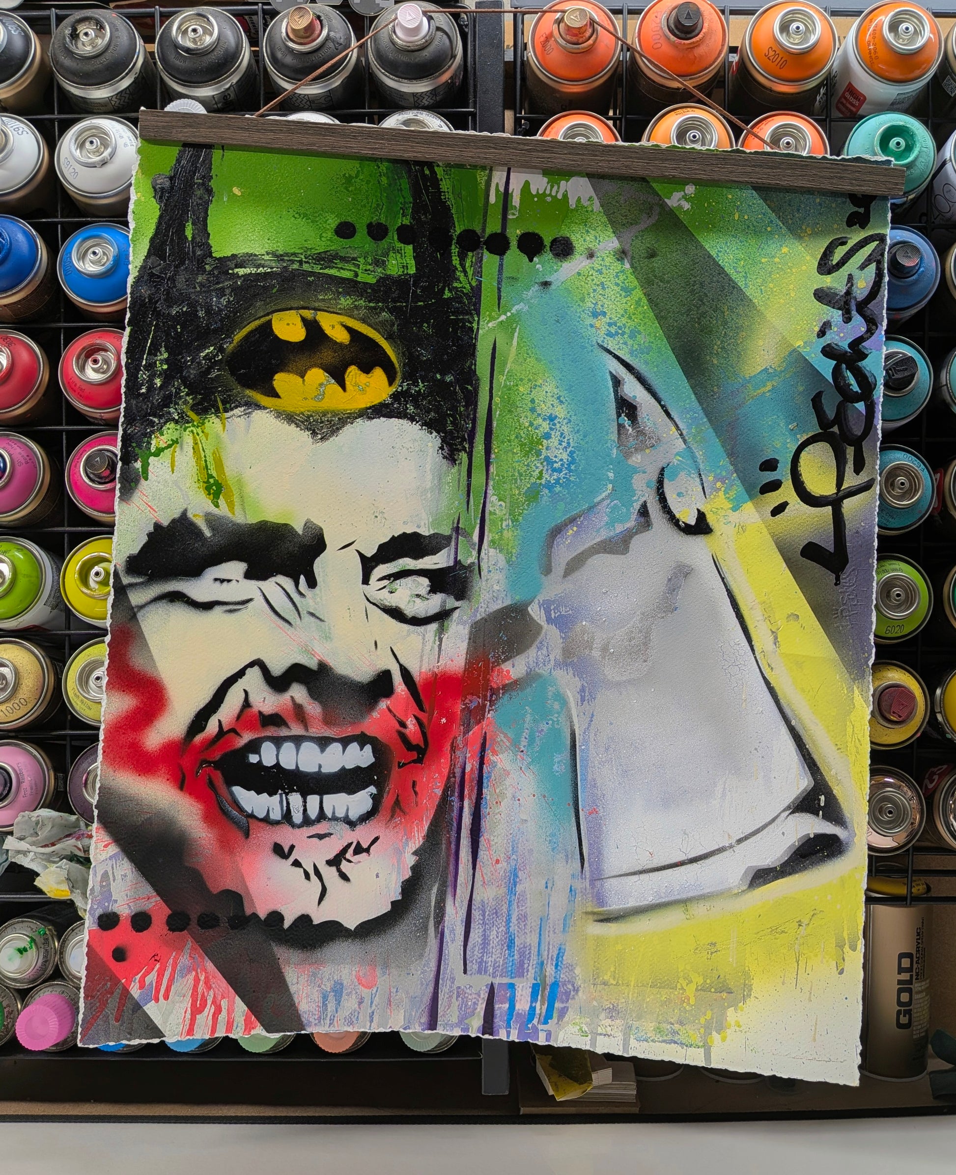 Artistic depiction of a face with a bat symbol and a knife, surrounded by spray paint cans.