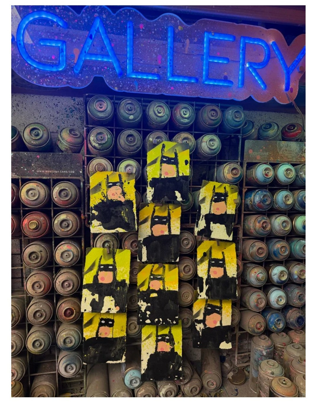 Artistic display of superhero figures in front of a 'GALLERY' sign with neon lights.