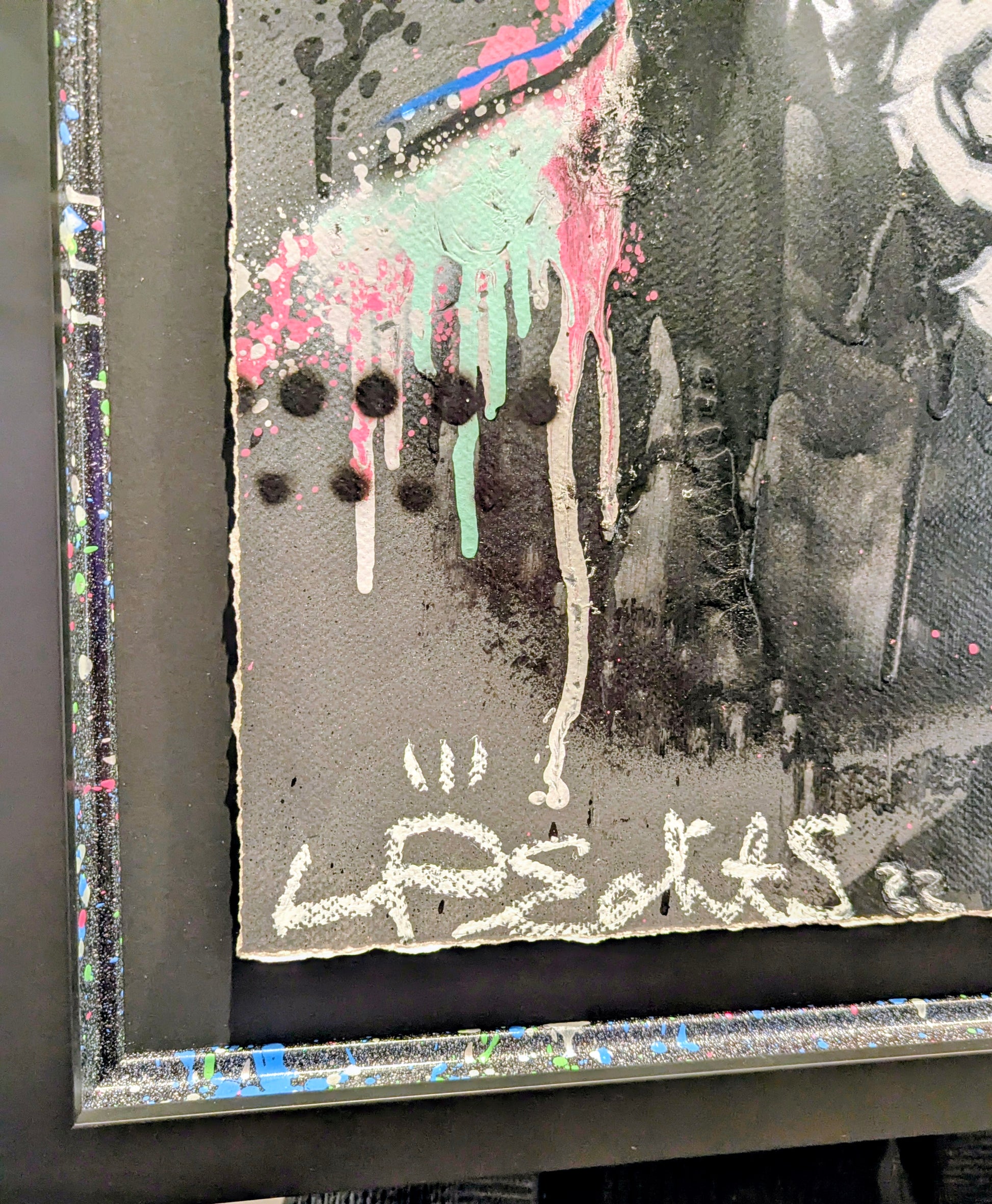 Abstract art piece with splashes of color and a signature on a dark background