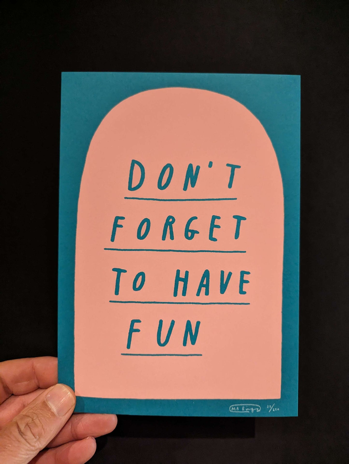 MR BINGO 'DON'T FORGET TO HAVE FUN' Ltd Ed Print, text is hand written style on a salmon pink tombstone against a teal background. card is being held in bottom left corner against a black background