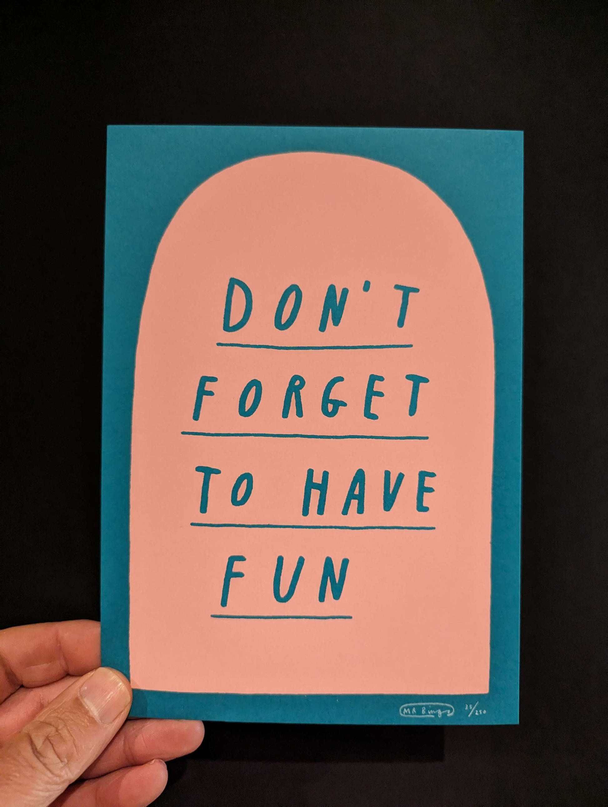 MR BINGO 'DON'T FORGET TO HAVE FUN' Ltd Ed Print, text is hand written style on a salmon pink tombstone against a teal background. card is being held in bottom left corner against a black background