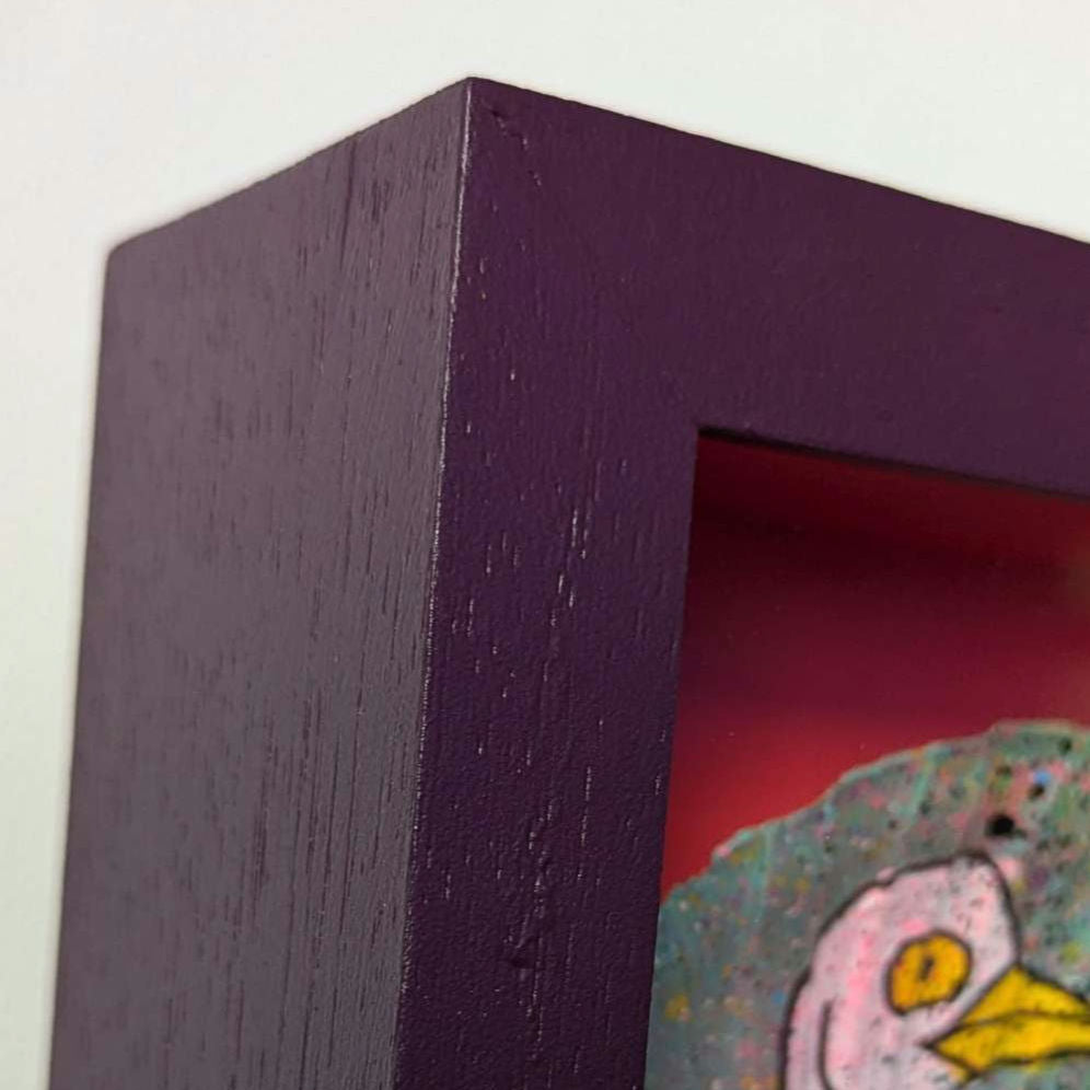 corner of small but chunky purple frame, deep purple with wood grain showing.