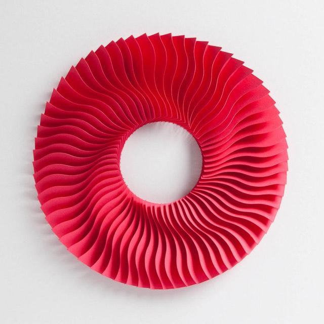 Paul Spencer paper sculpture. its round shaped with a clear middle, the pink paper is layered to create a wave effect.