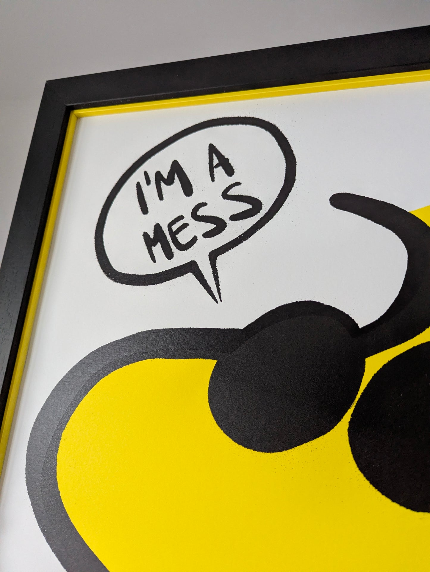 Framed artwork with a yellow circle, black speech bubble, and text 'I'm a mess' on a white background.