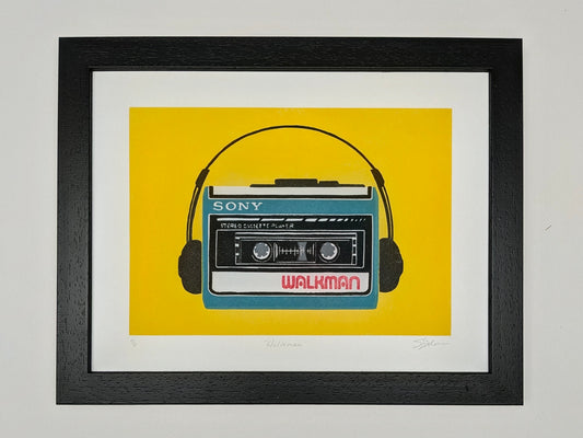 A framed art print featuring a retro Sony Walkman cassette player with headphones on a bright yellow background, enclosed in a black frame with a white mat.