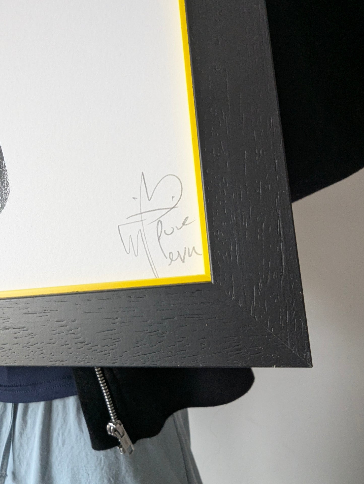 Framed artwork with a signature on a plain background