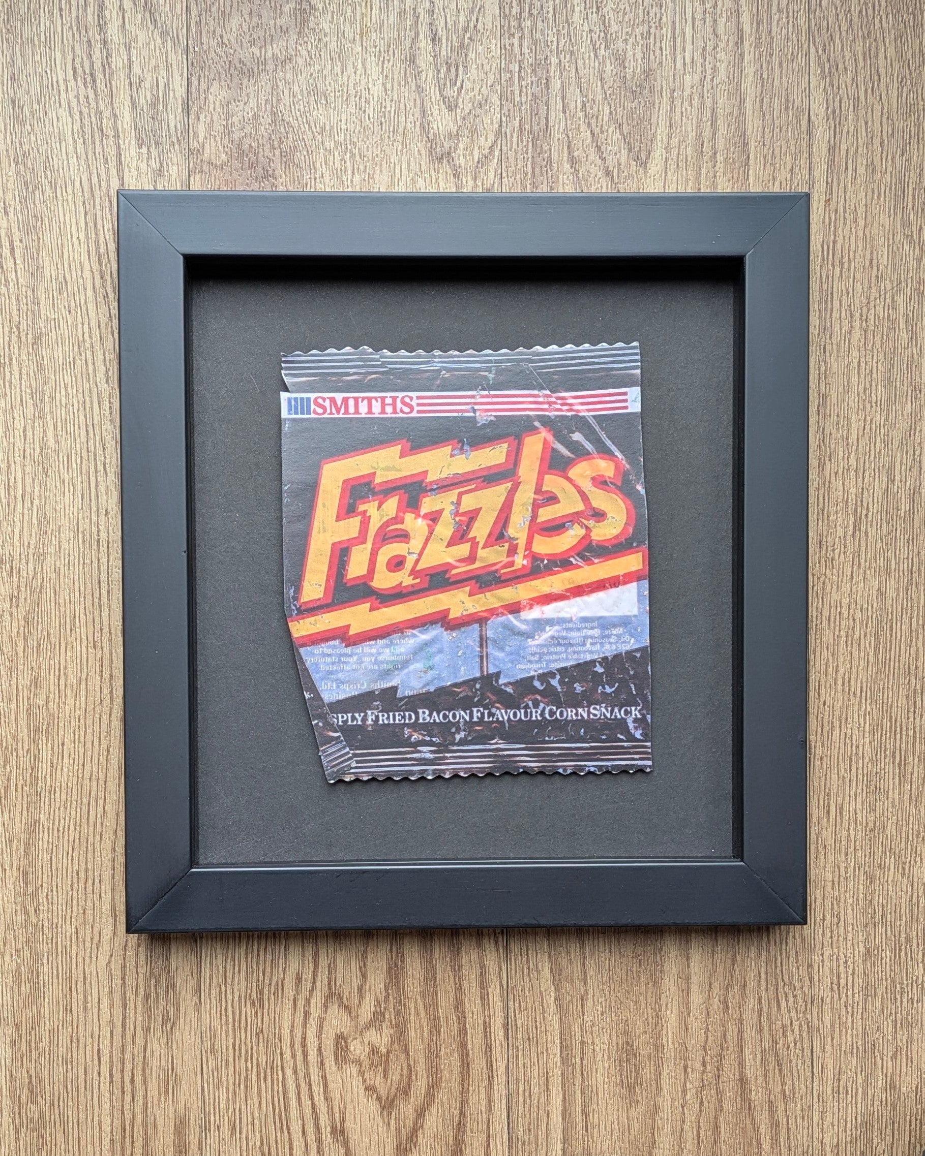 Framed Smith's Fizzles snack packet on a wooden surface