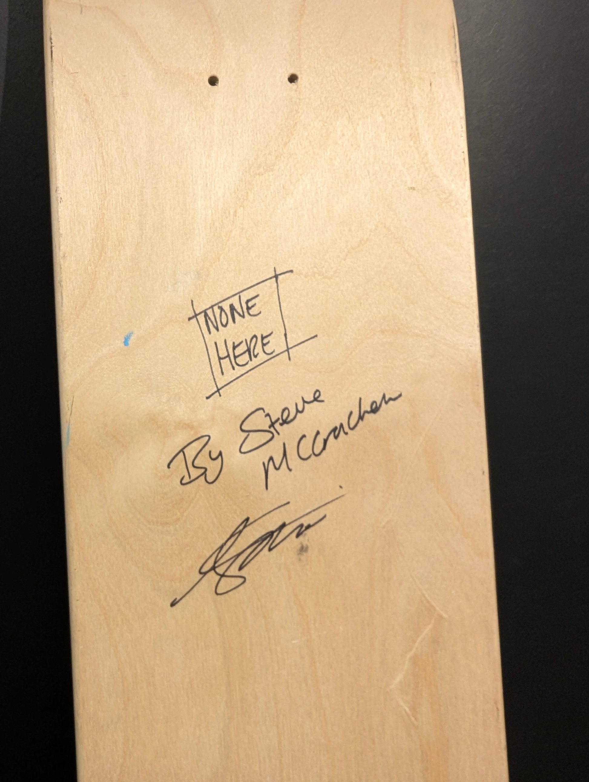 Wooden skateboard deck with handwritten text on a black background