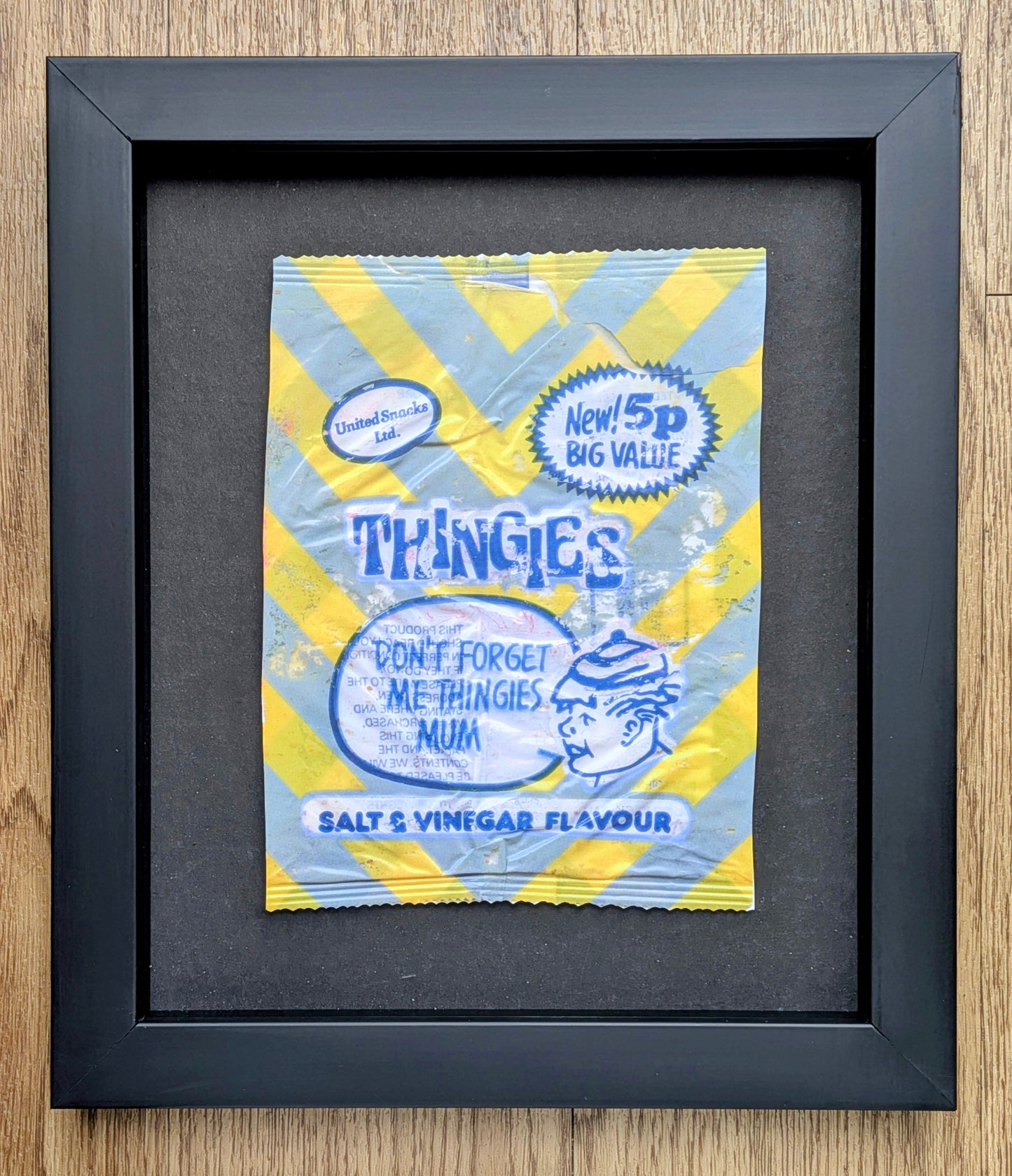 Framed miniature packet of 'THINGIES' salt and vinegar flavour on a wooden surface