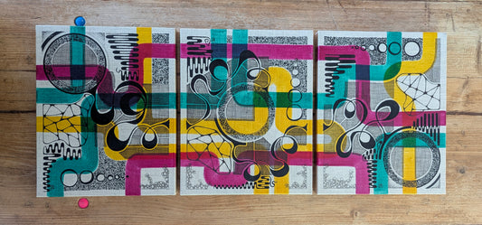 triptych colourful doodles on off white panels, placed on wooded table