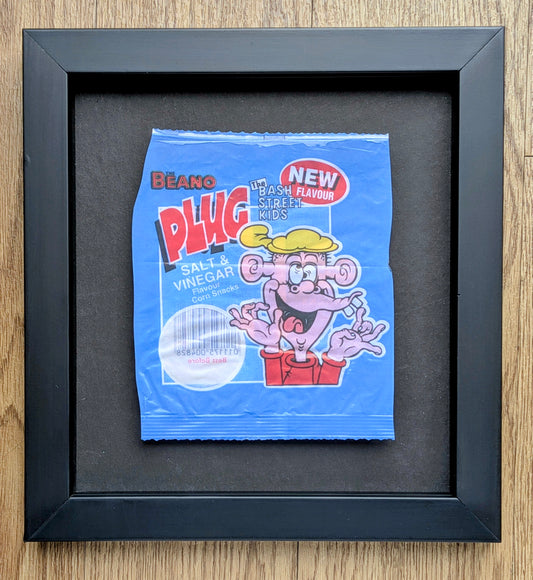 Framed blue packet of Beano Plug Salt & Vinegar crisps on a wooden surface
