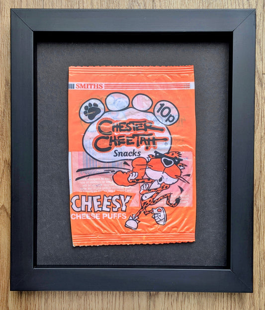 Framed vintage-style Cheetos snack packet on a wooden surface