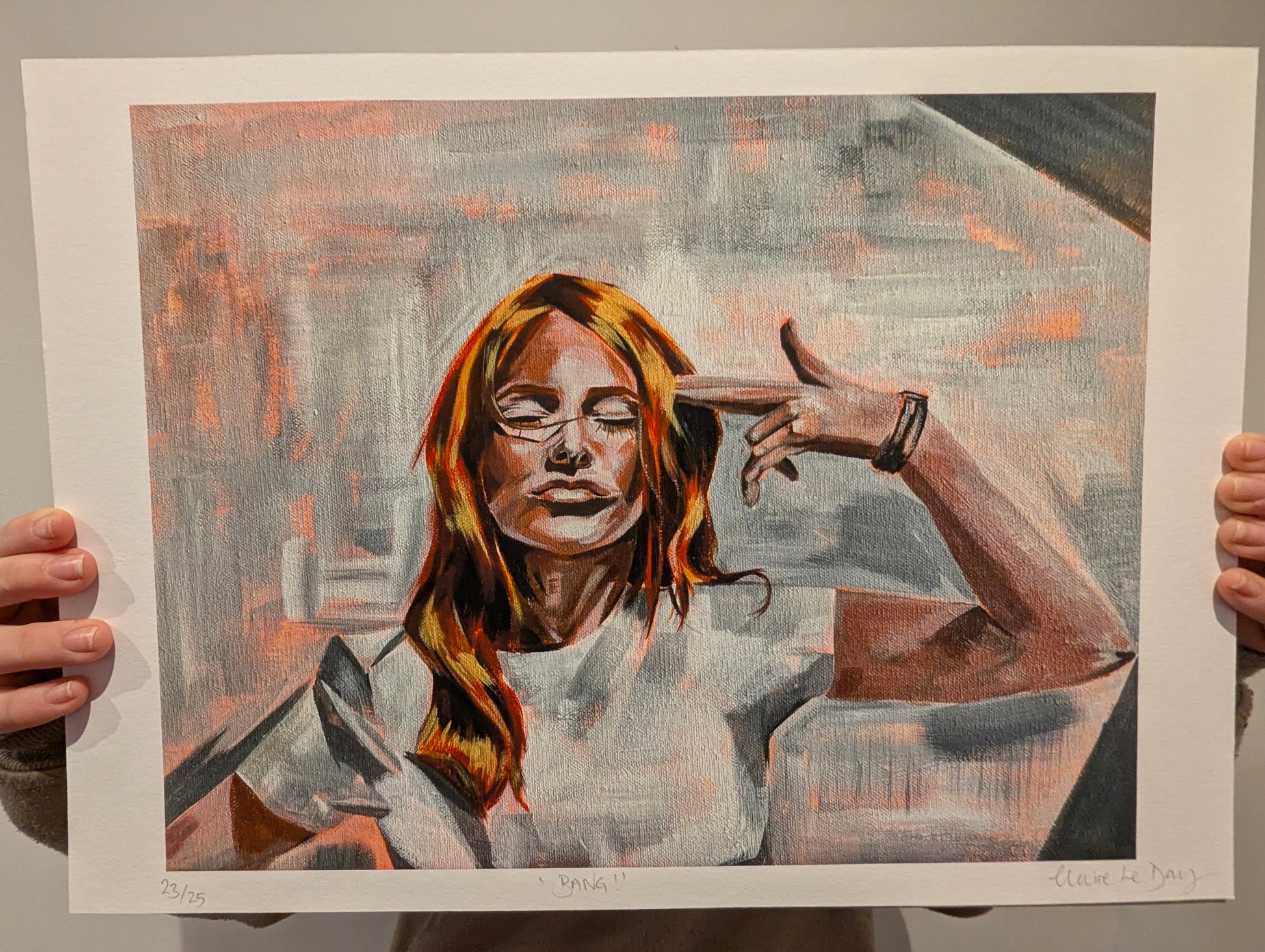 Artistic depiction of a woman with gun hand held to her head, white boarder. artwork being held by person against white wall