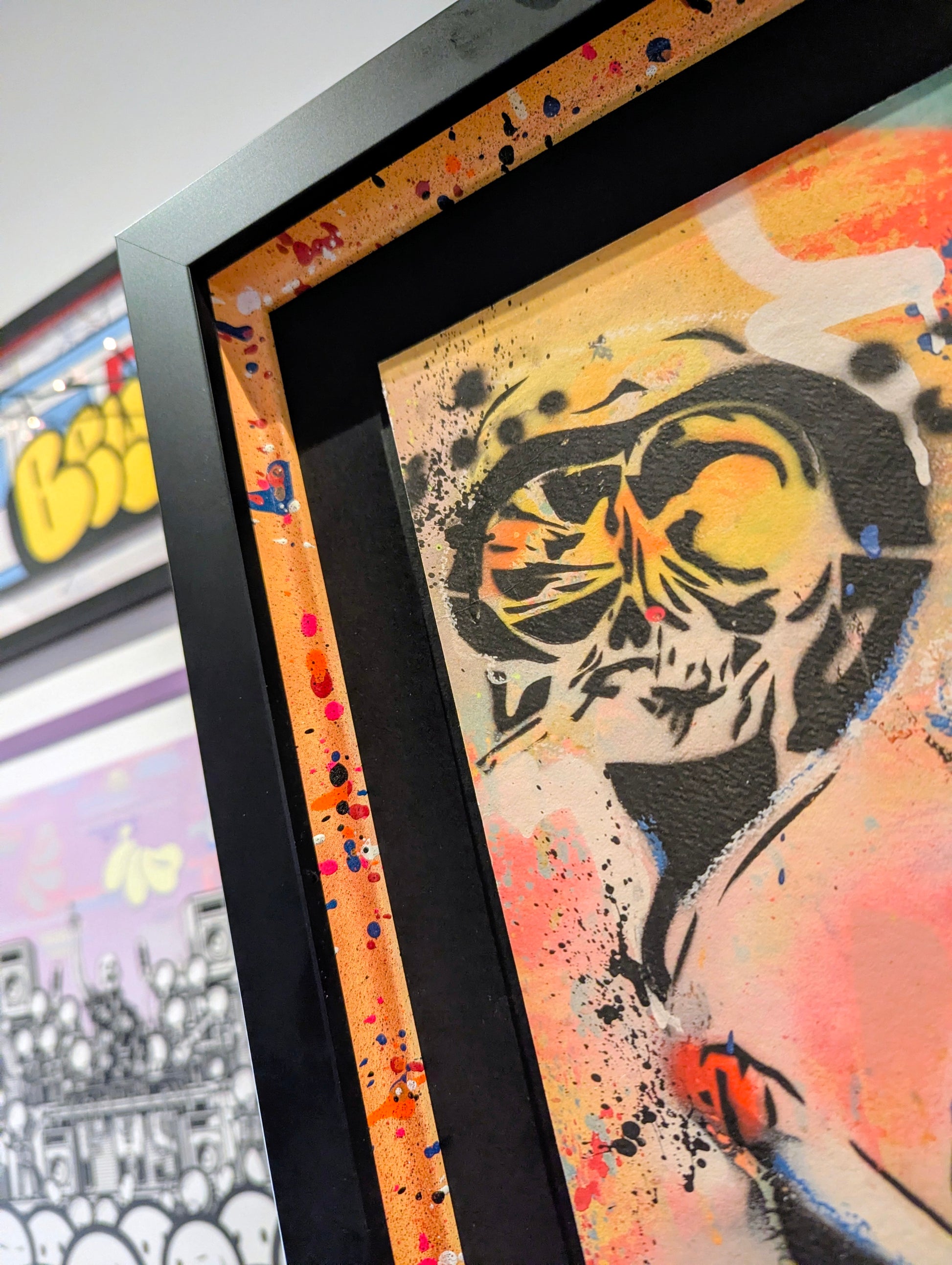 Framed artwork with a colorful abstract design and visible brand logo.