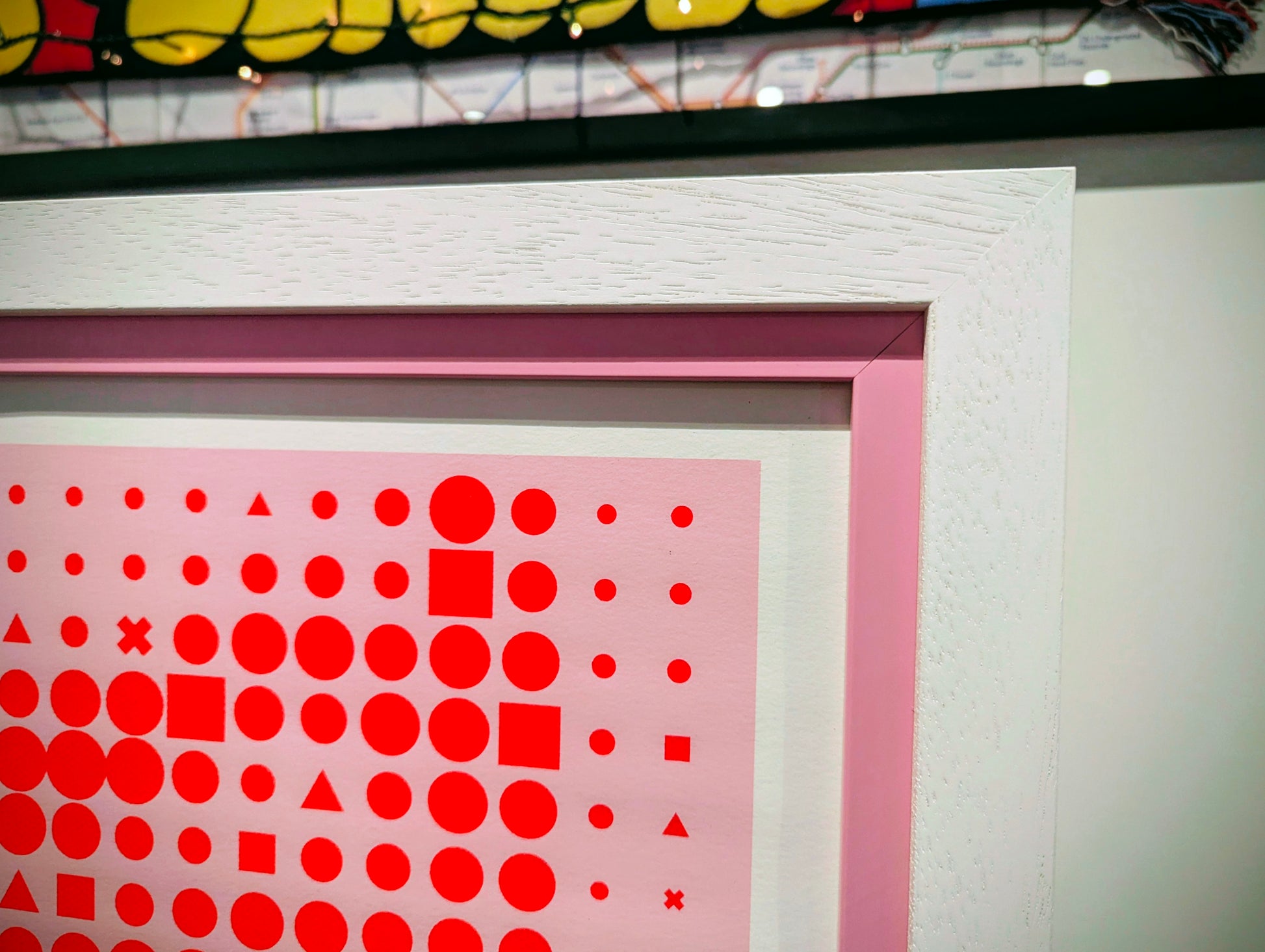 Framed artwork with red geometric patterns on a white wall