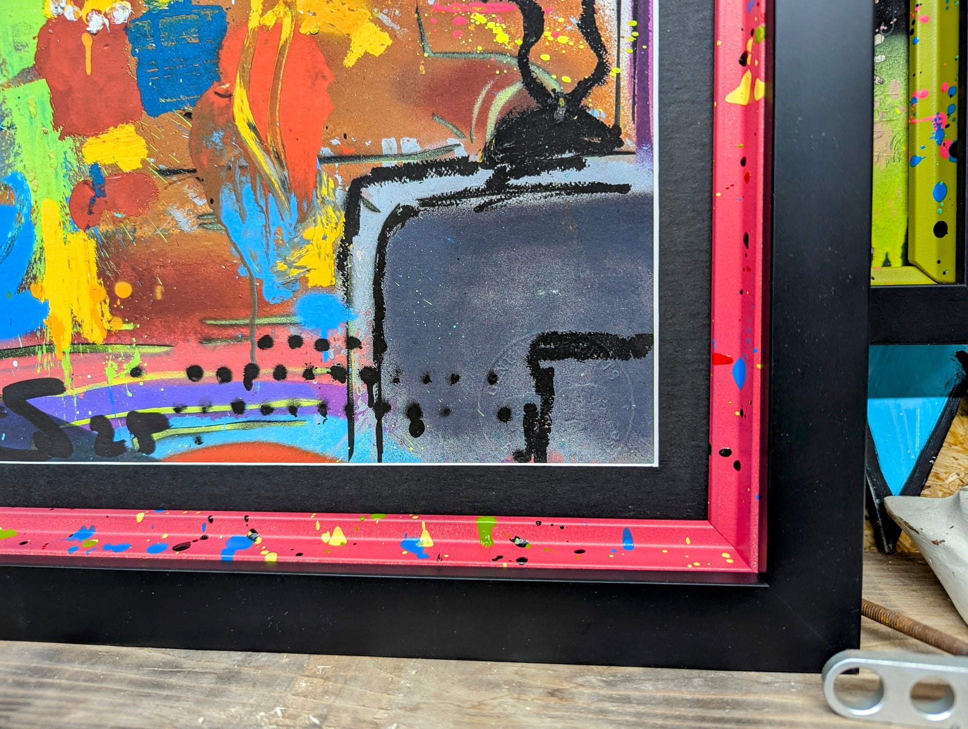 close up of the smooth black picture moulding and the internal custom painted frame, frame is red with blue yellow green splatters