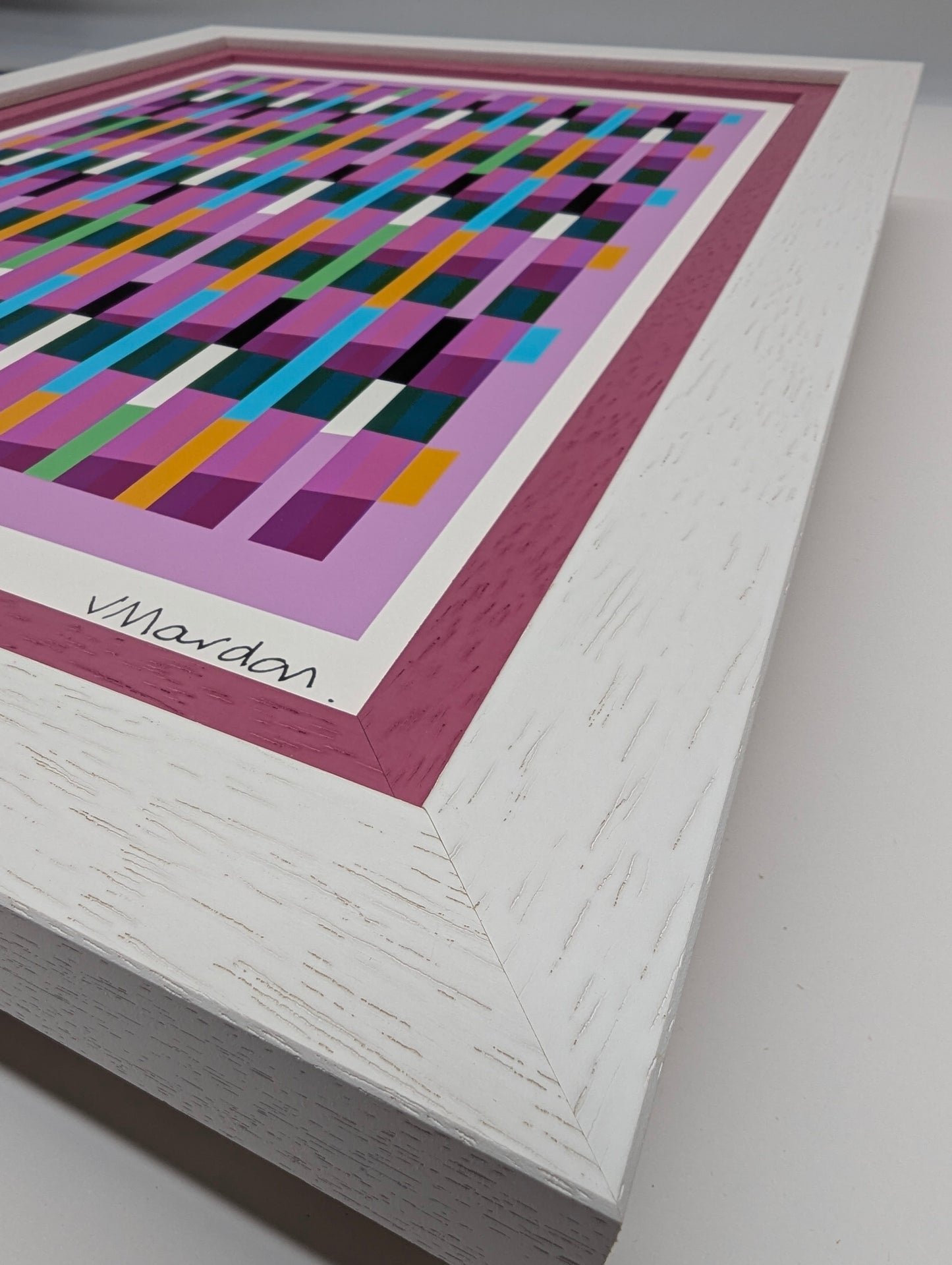 Framed abstract artwork with colorful geometric design on a white surface