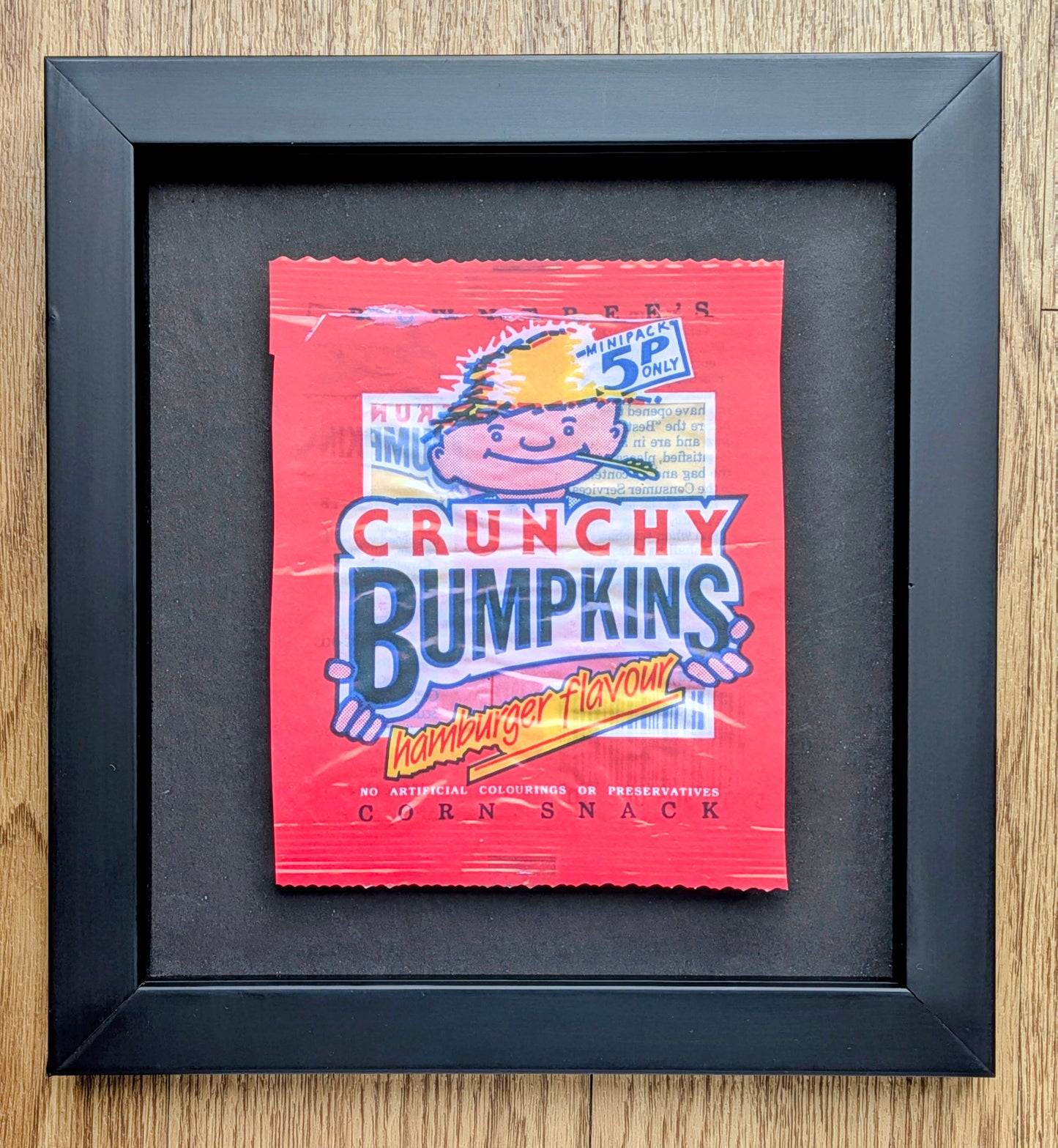 Framed poster of a Crunchy Bumpkins corn snack packet on a wooden surface